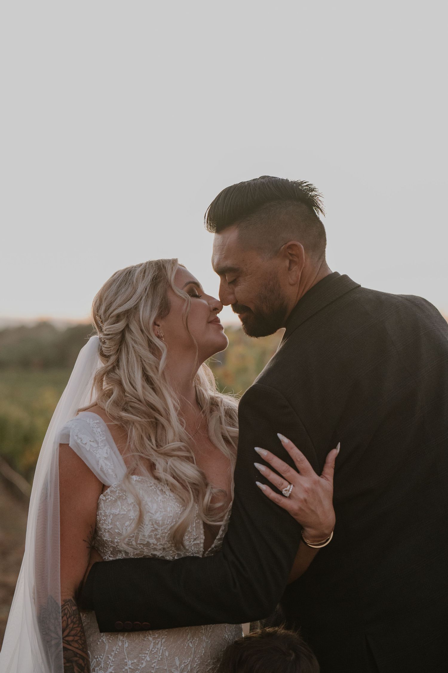 Intimate wedding portraits captured against a moody sky in a vineyard setting.