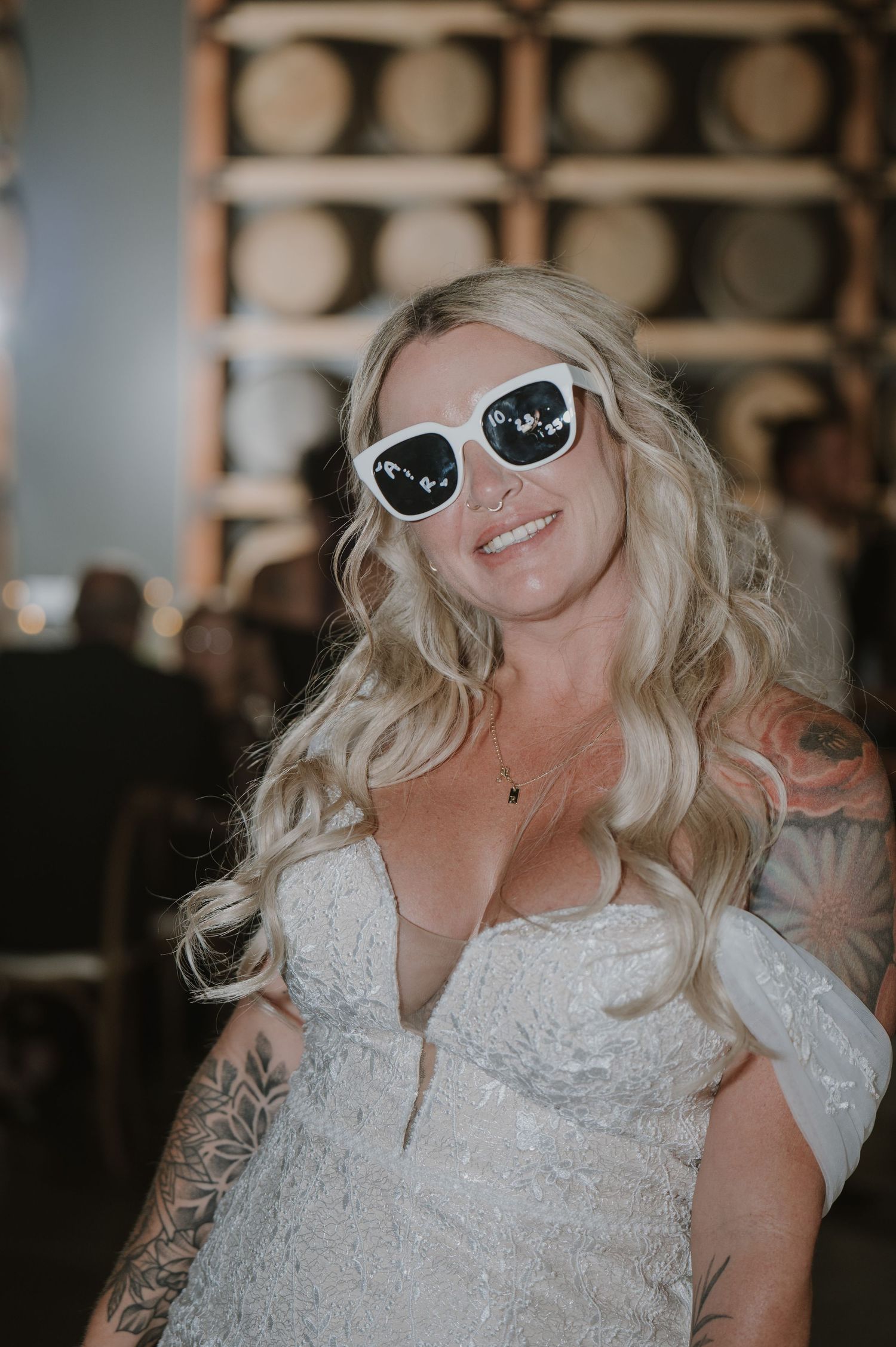 Bride wearing white sunglasses and lace dress dancing at reception.