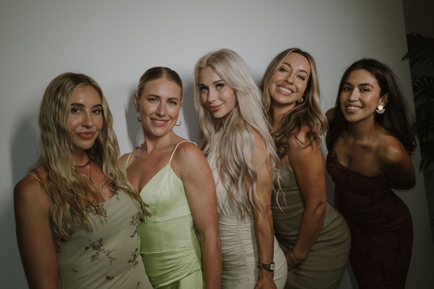 Bridesmaids in neutral tones pose together for wedding party photos.