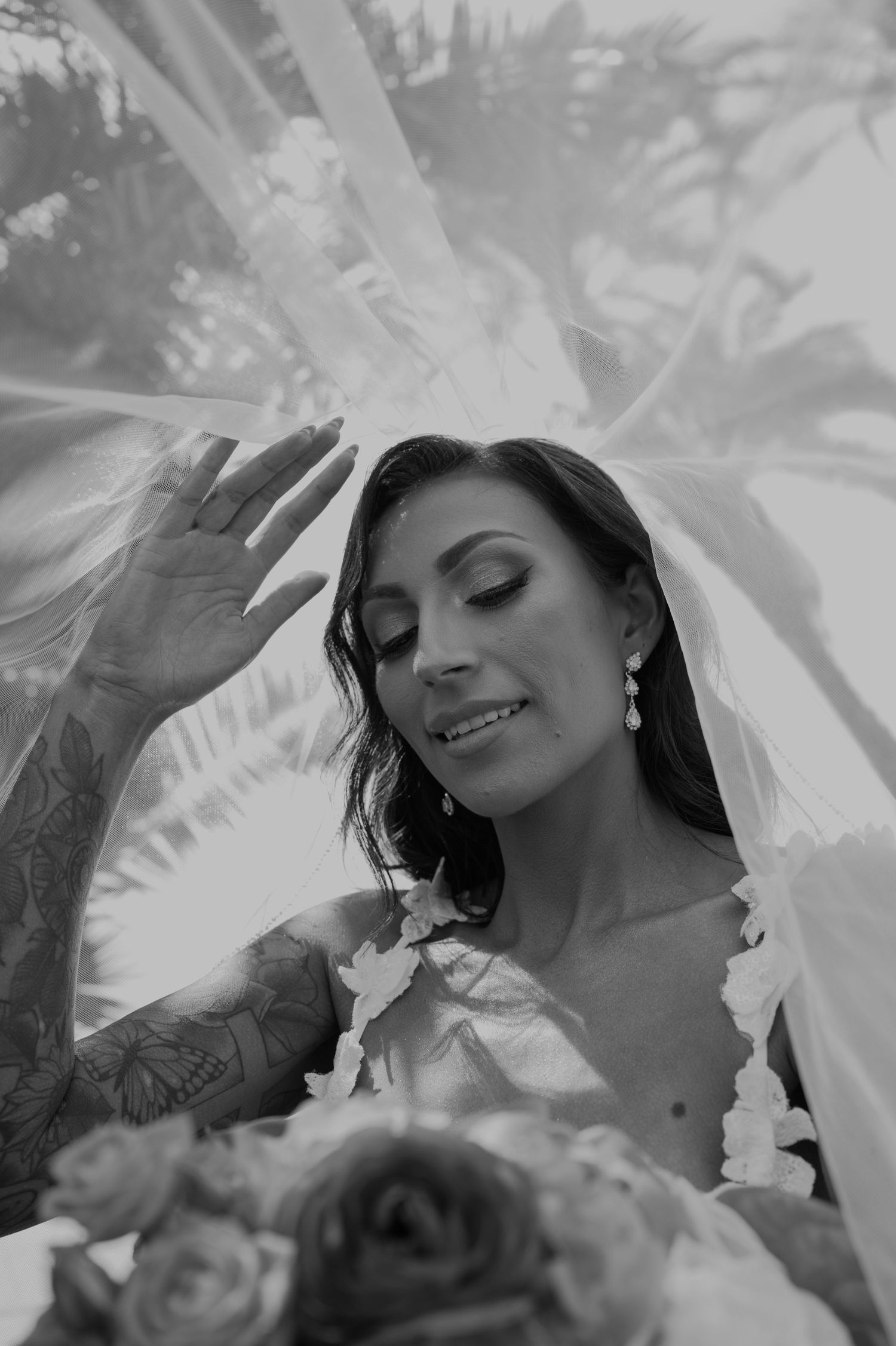 An artistic black and white bridal portrait showing details of the veil and makeup.