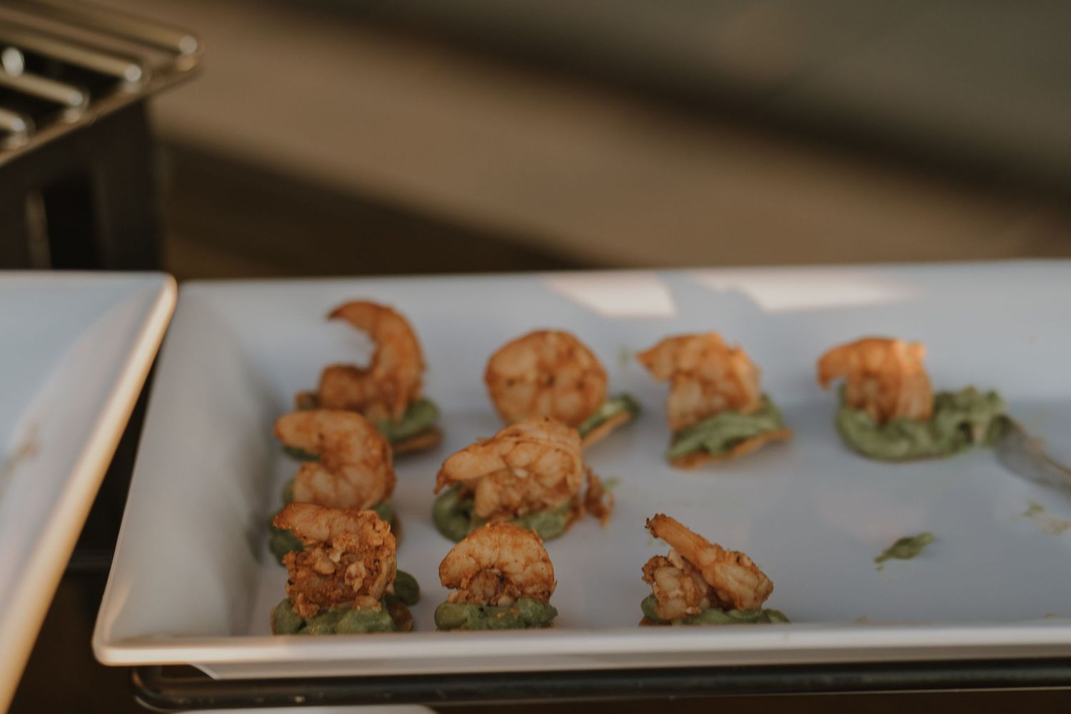 Elegant appetizers plated on white rectangular serving dishes in a restaurant setting.