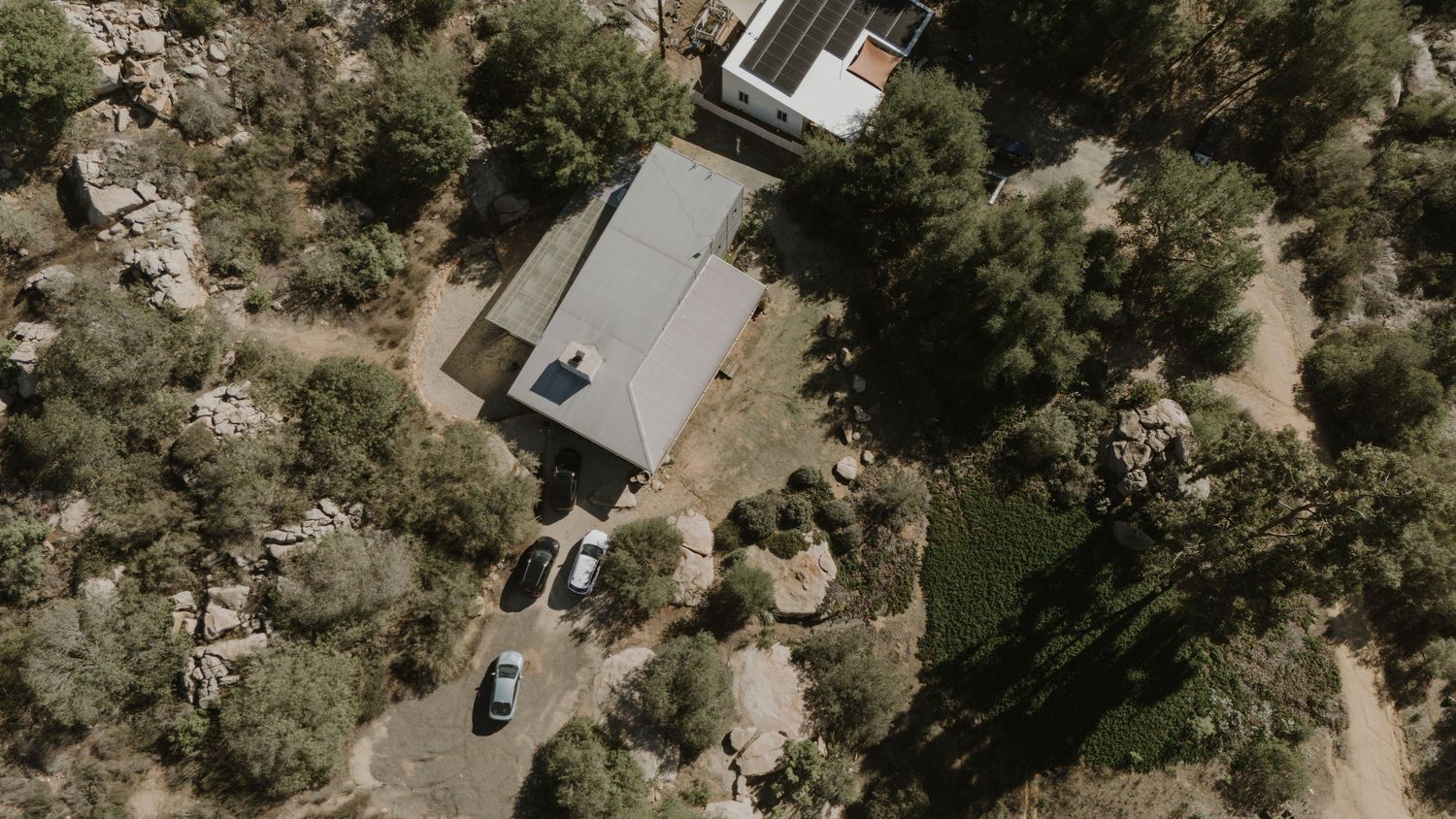 Aerial view of buildings and parked cars in a desert landscape.