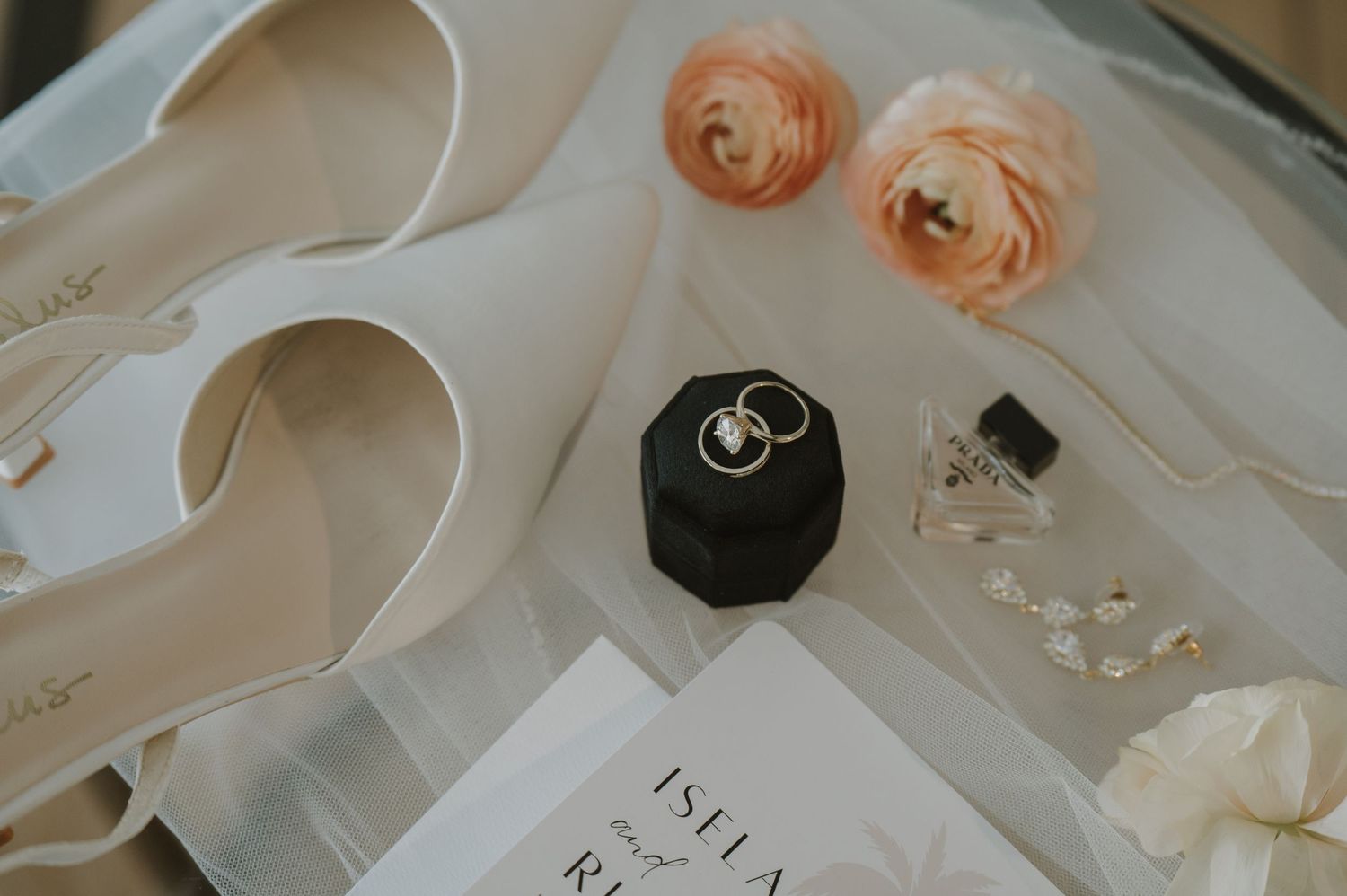 Wedding stationery and rings styled with soft peach roses and elegant details.