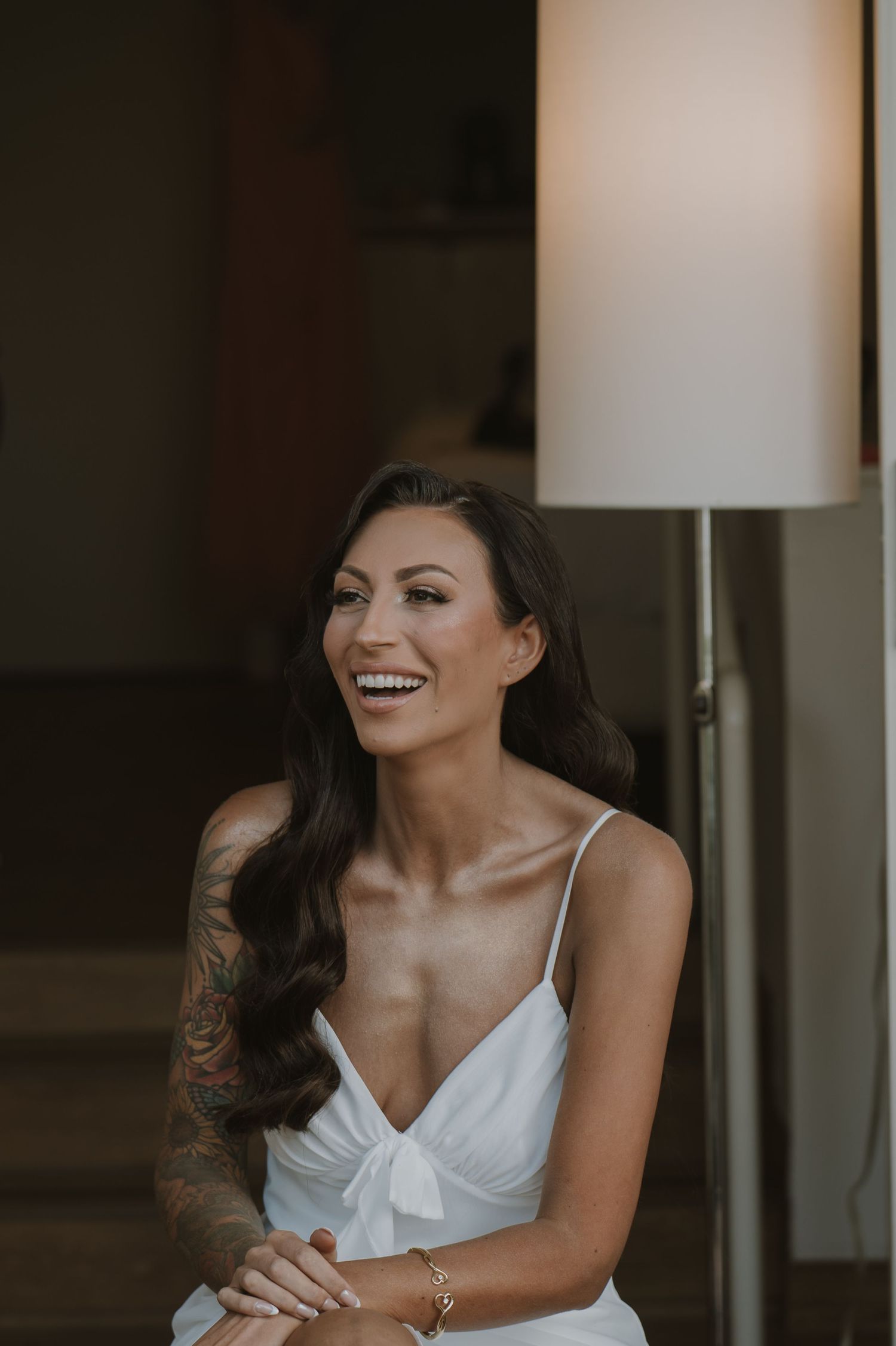 Bride in white dress laughing during wedding preparations.