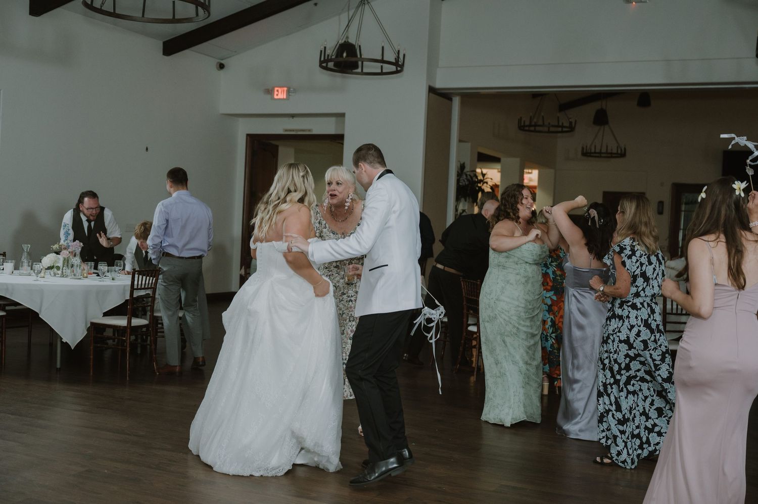 Bride dancing with guests including mother on wedding reception dance floor.