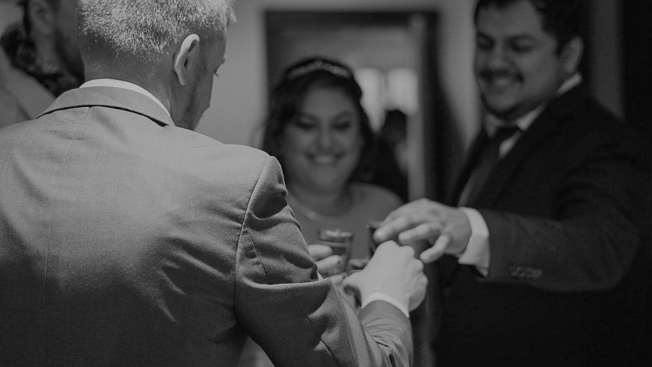 Black and white wedding photo of bride and groom exchanging rings during ceremony.
