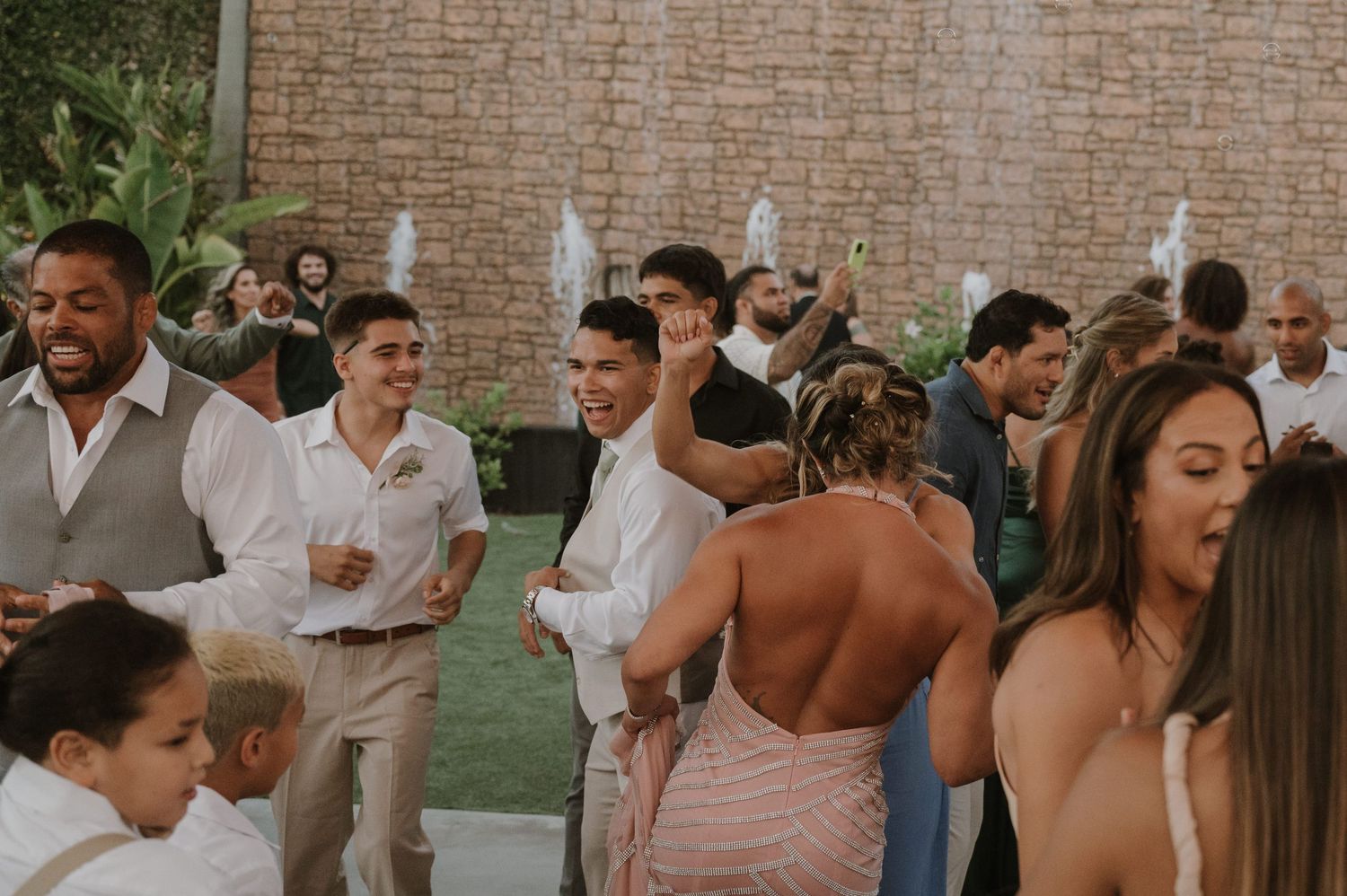 Guests celebrate and dance together at a lively outdoor wedding reception party.
