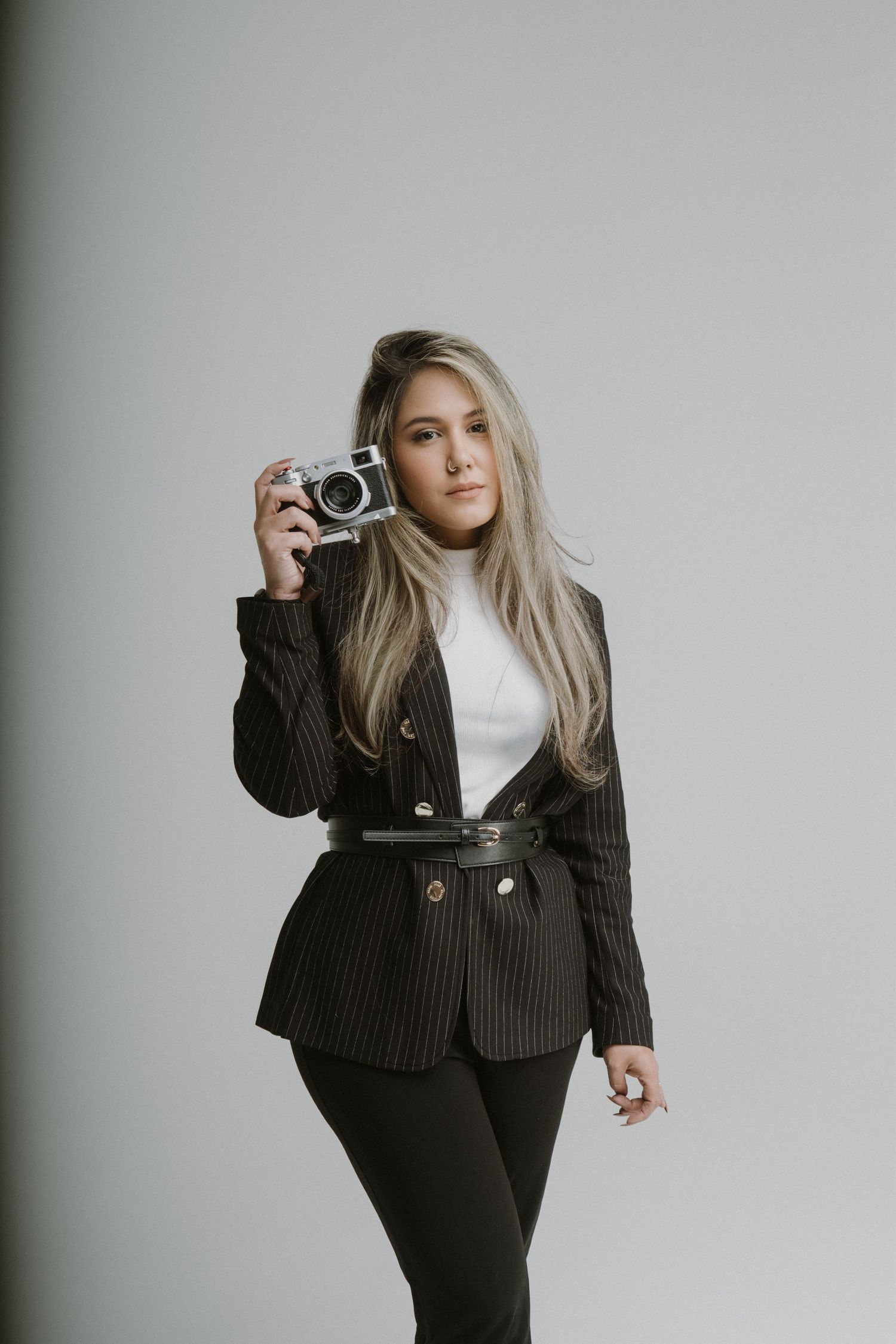 Fashion portrait series with vintage camera against grey background.