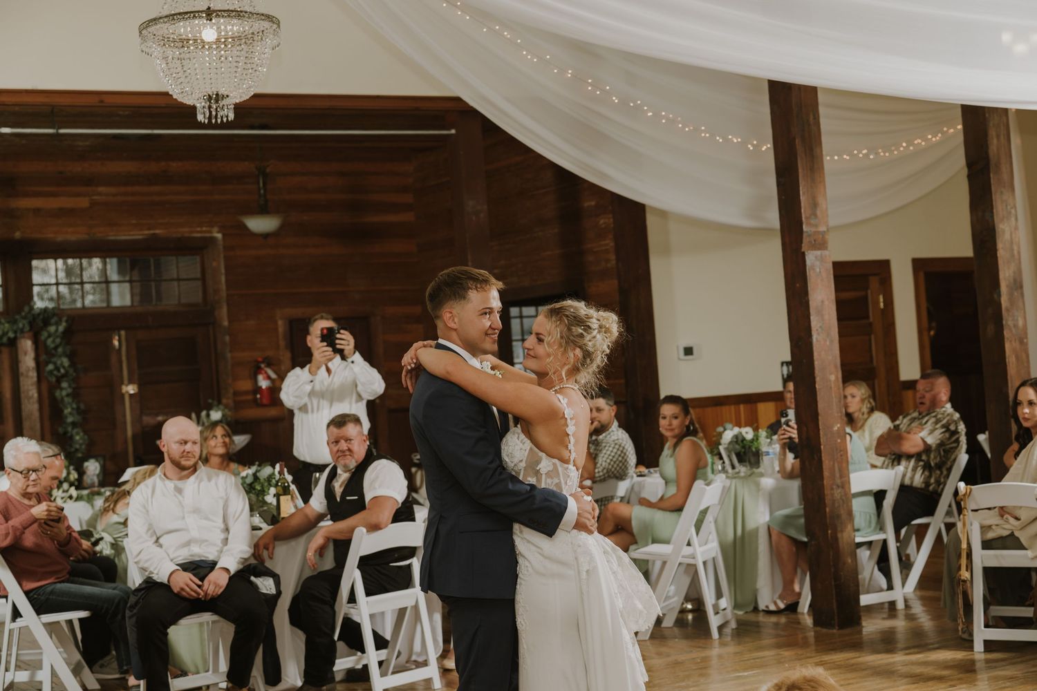 Wedding reception venue with white draping and chandelier decorations.