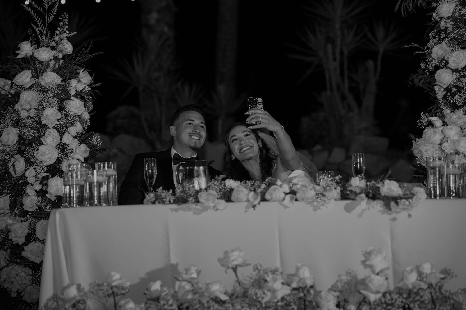 Elegant white floral arrangements and table settings at a wedding reception.