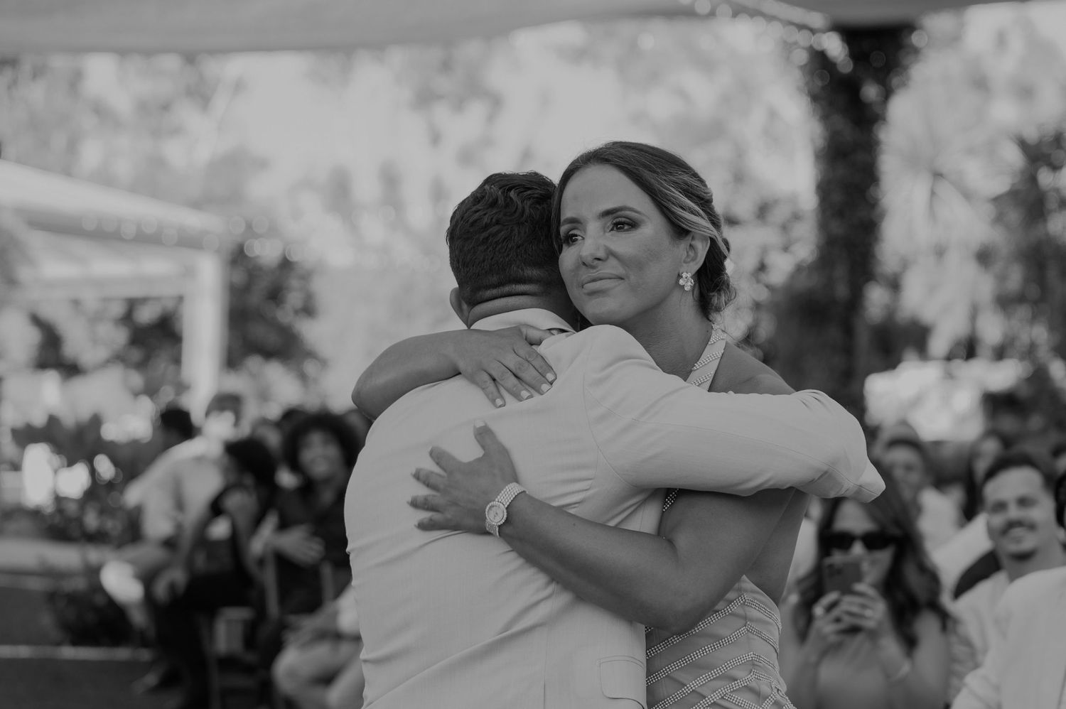 Black and white photo of a bride and groom sharing an emotional embrace on the dance floor at their wedding reception.