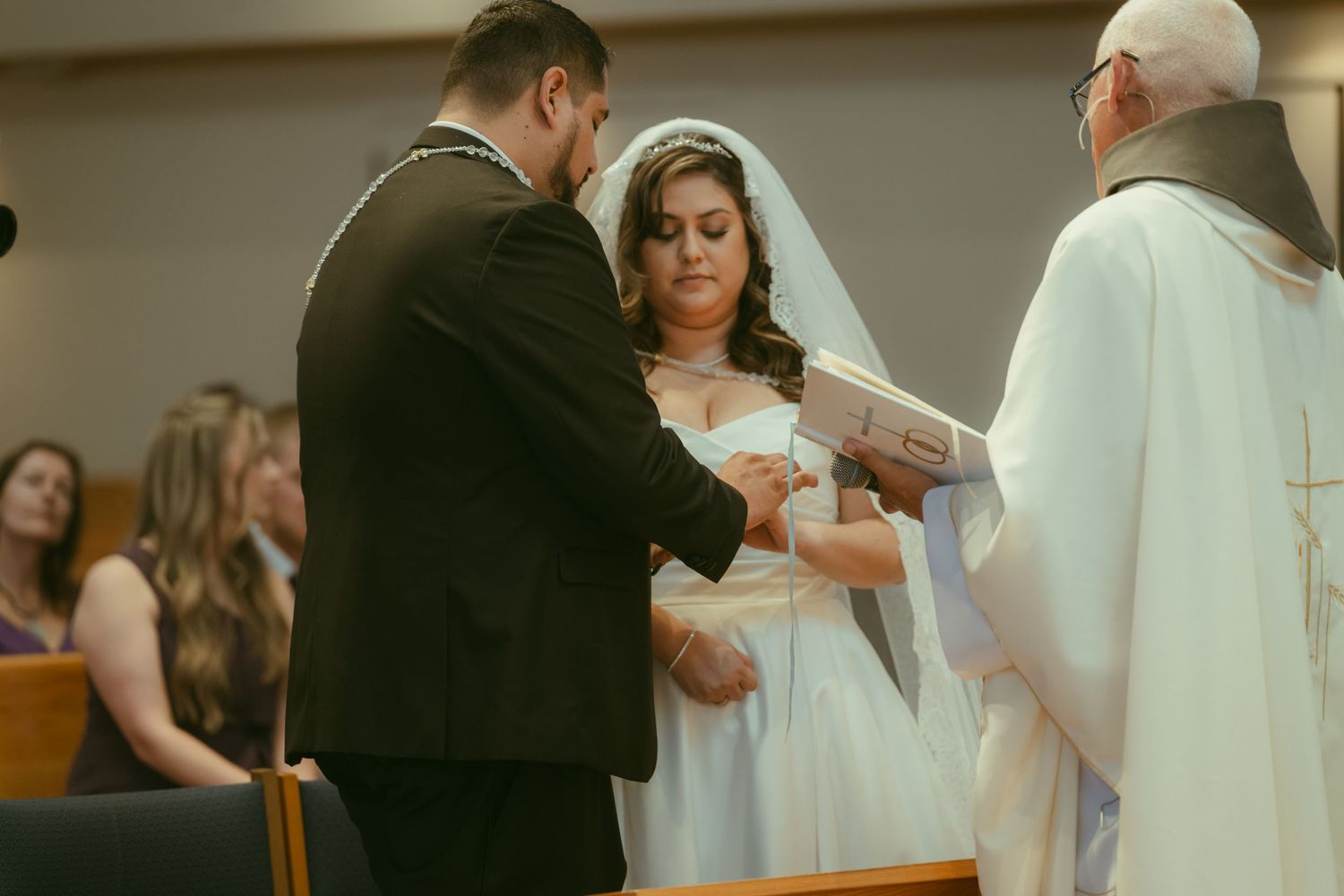 Bride and groom exchanging rings during wedding ceremony with officiant.