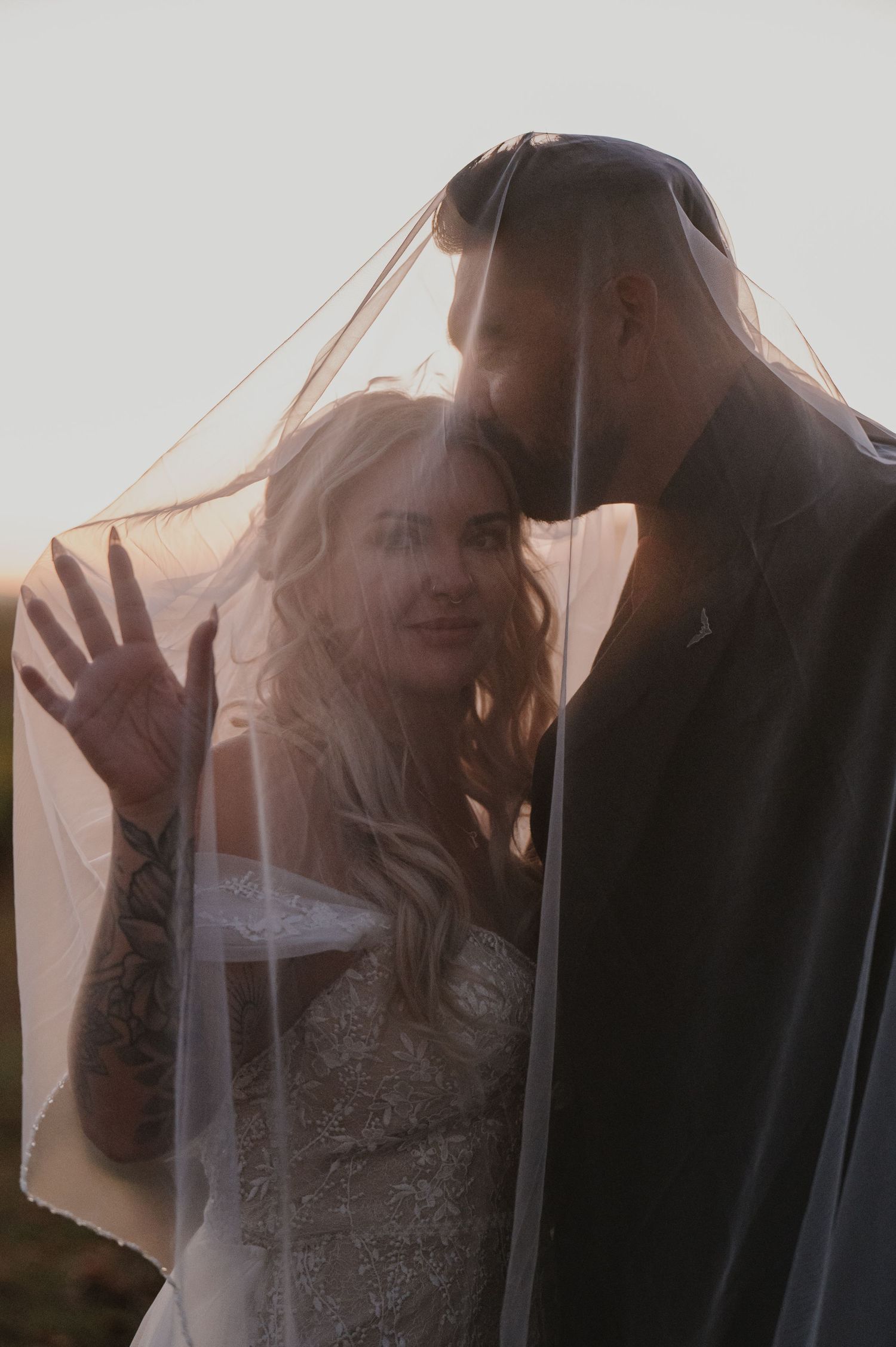 Dreamy backlit wedding portraits show tender moments through a sheer veil.
