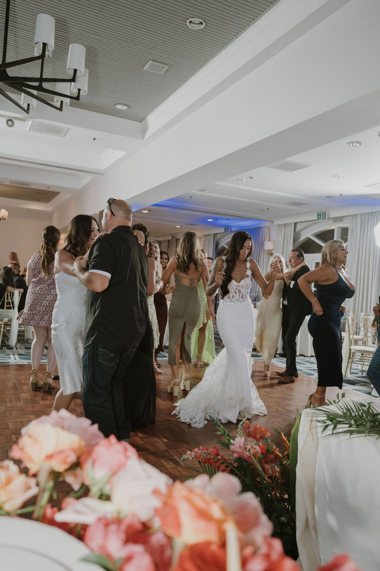 Wedding reception dance floor filled with guests celebrating under modern ceiling lights.