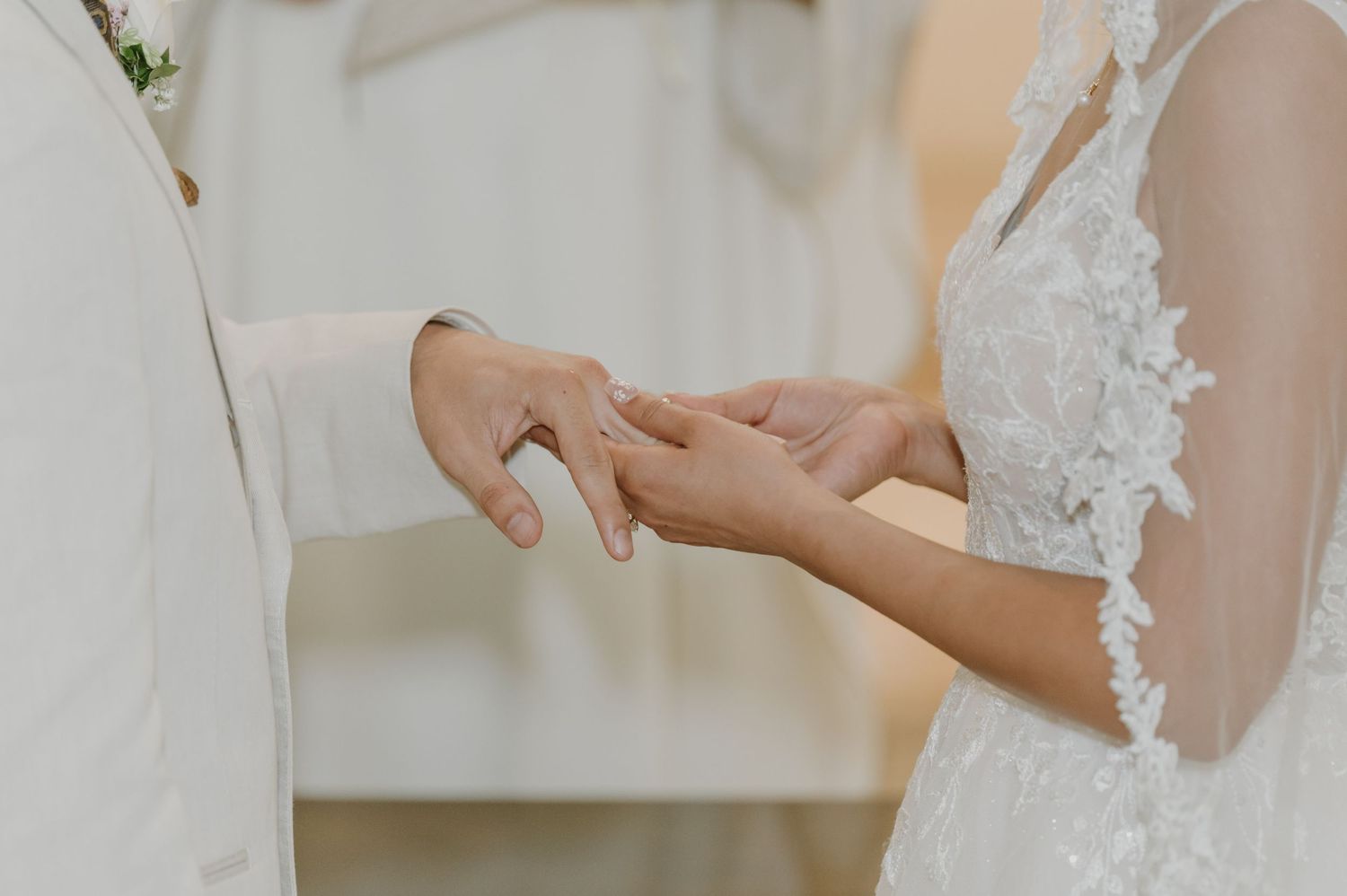 Close-up of groom placing wedding ring on bride's finger during church ceremony.