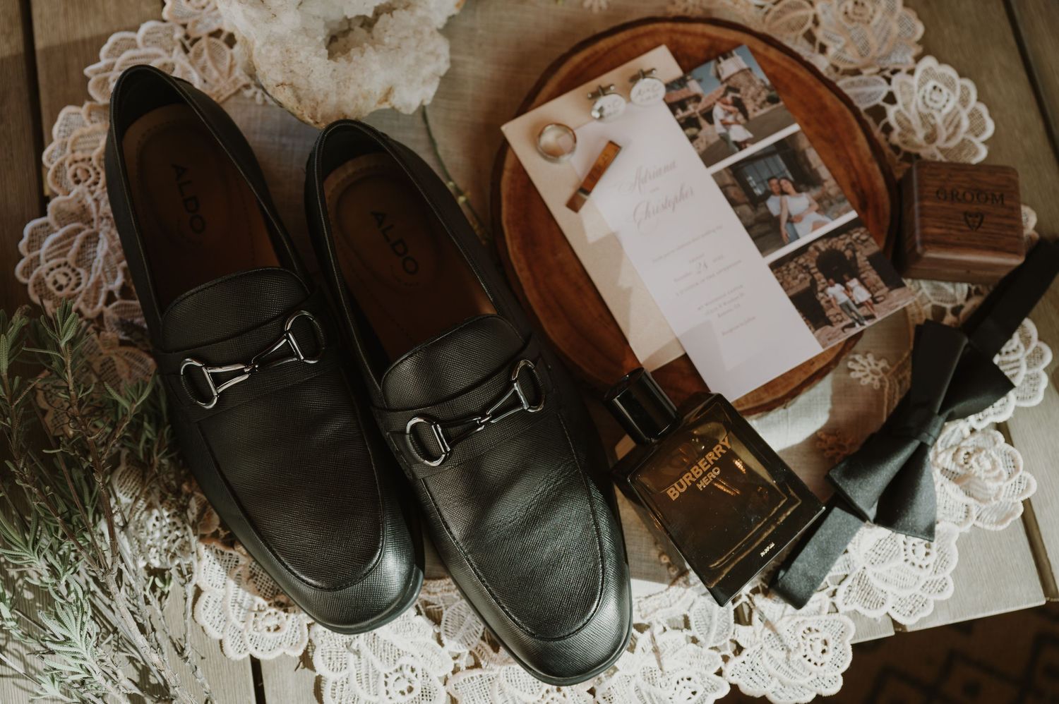Wedding details flatlay with leather shoes and photographs on wooden surface.