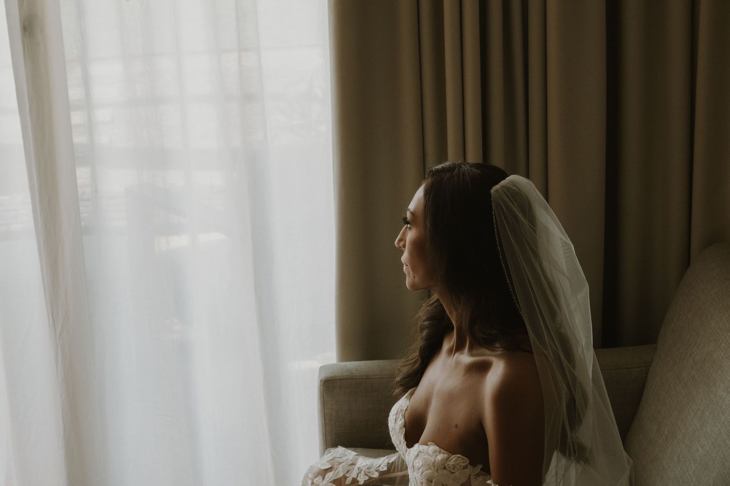 Soft, romantic bridal portrait silhouetted against sheer curtains in natural light.