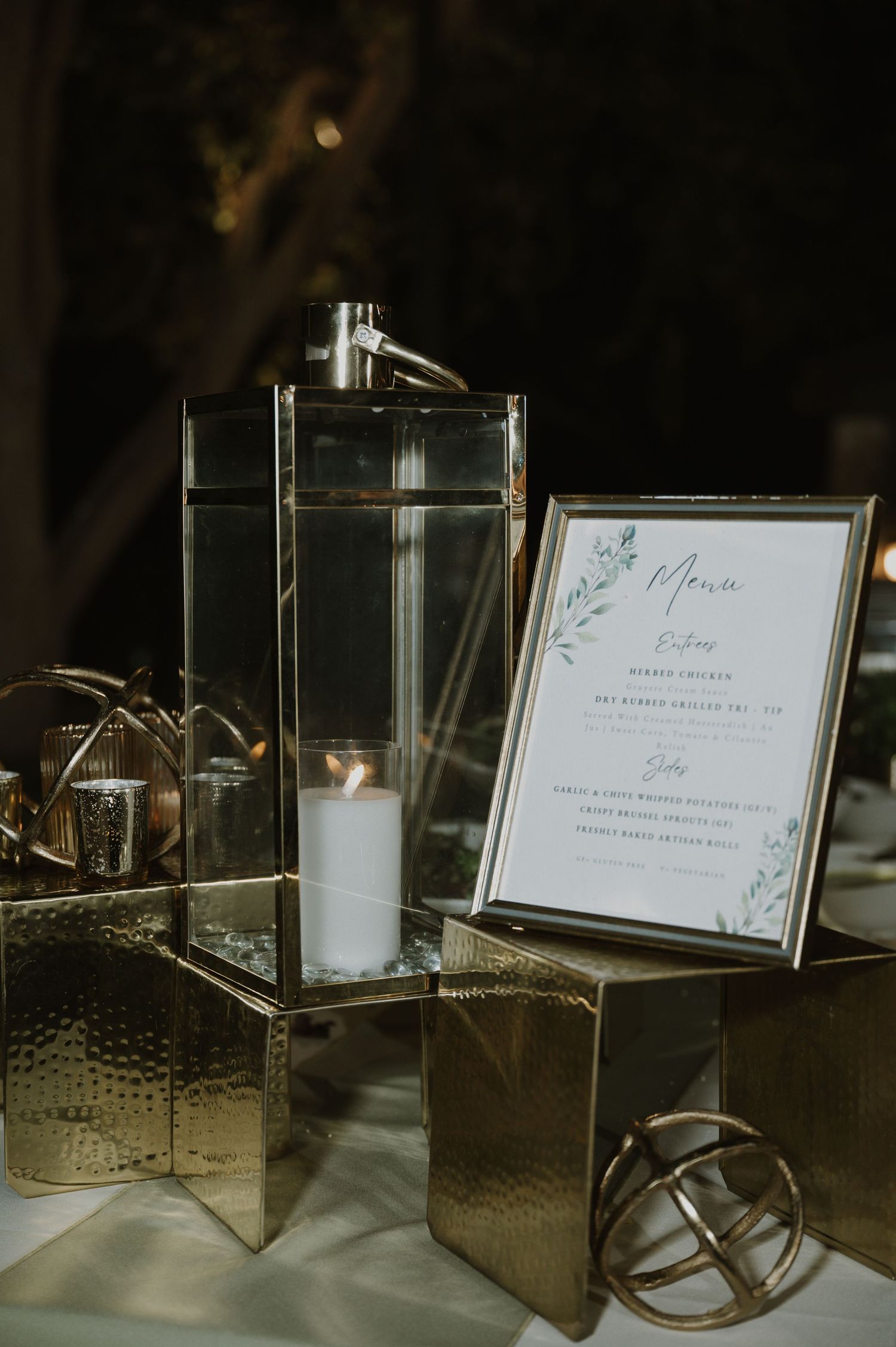 Elegant wedding reception display with mirrored signage holders and decorative candle holders on a textured surface.