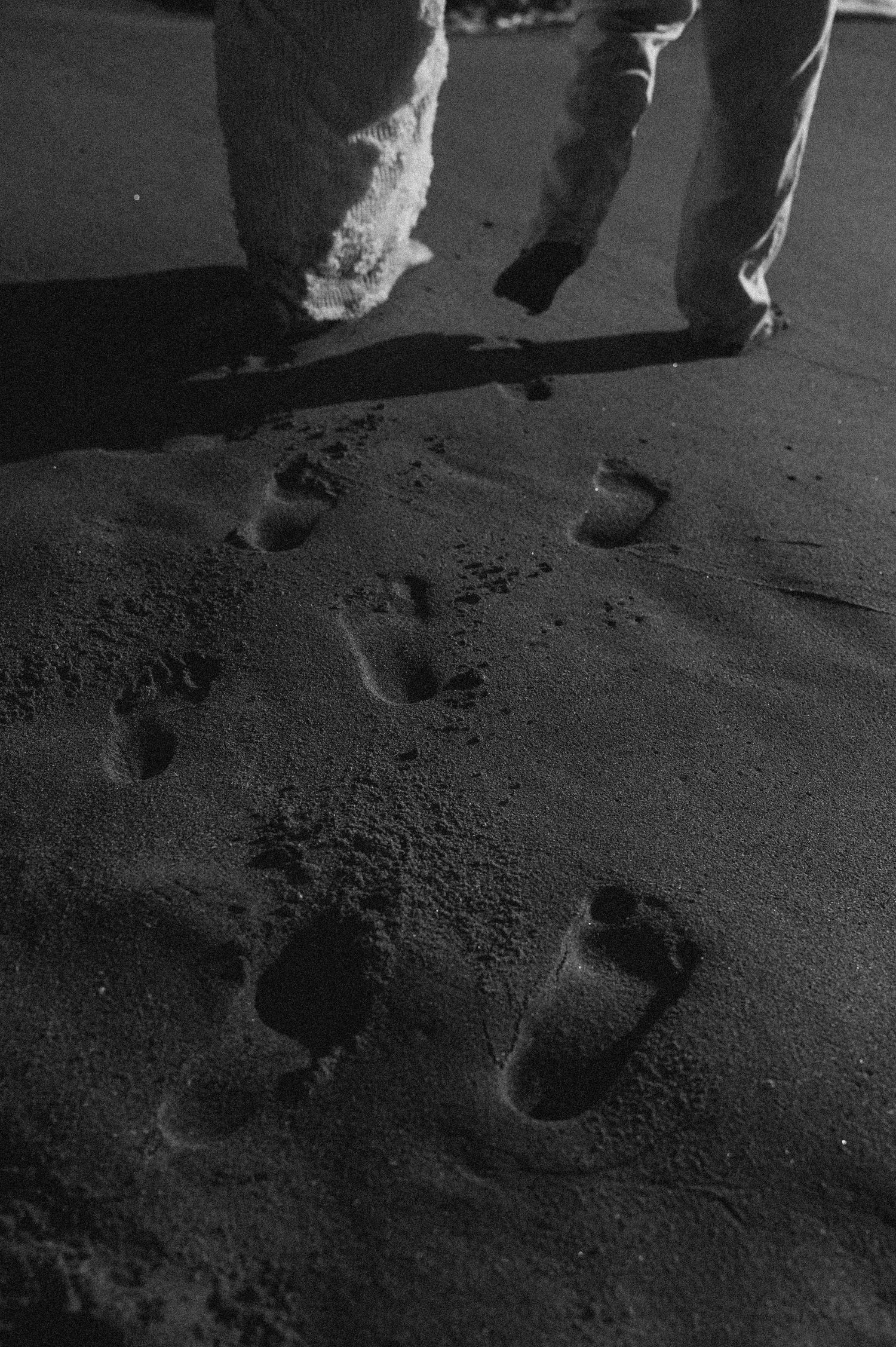 Footprints in dark sand create a romantic pattern during beach wedding photography.