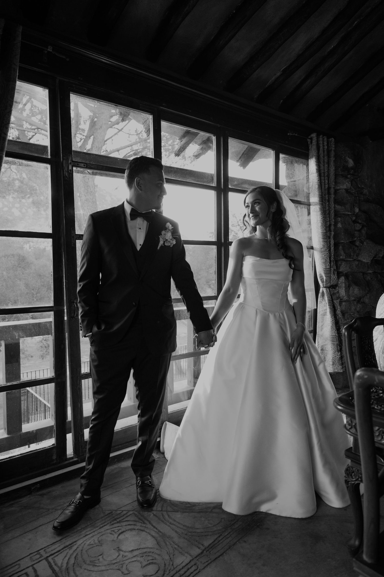 Black and white image of figures walking through an indoor venue with large windows.