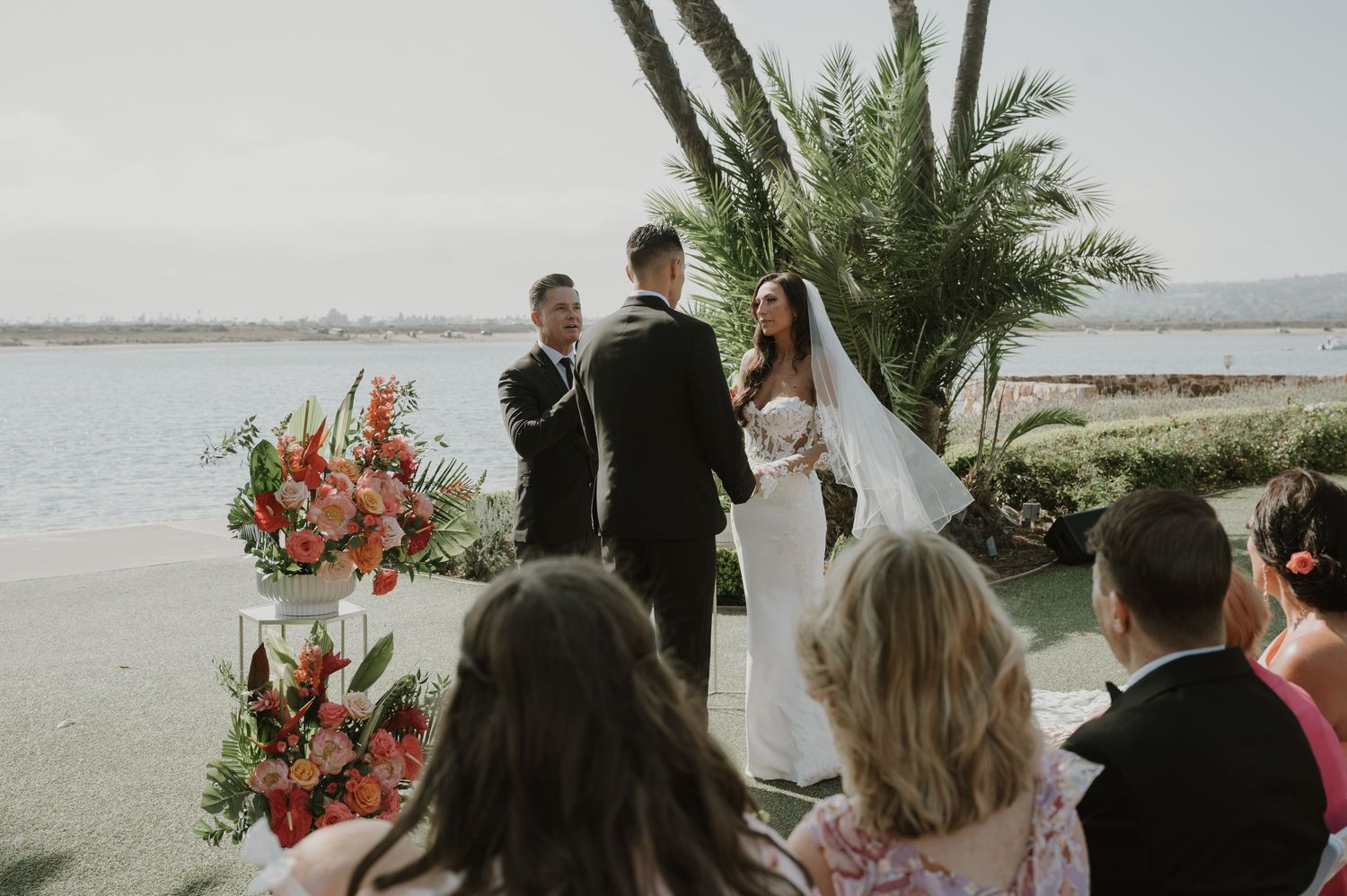 Outdoor wedding ceremony setup with tropical floral arrangements and ocean views.