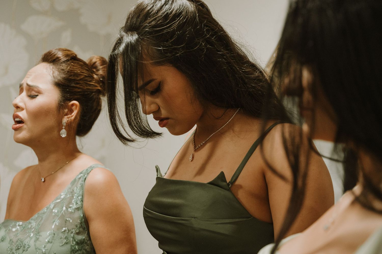 Bridesmaids in elegant green dresses preparing together before wedding ceremony.