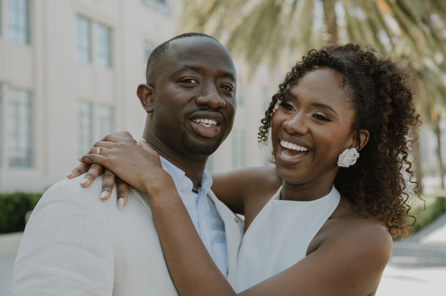 A joyful couple sharing laughter outdoors on a sunny day.