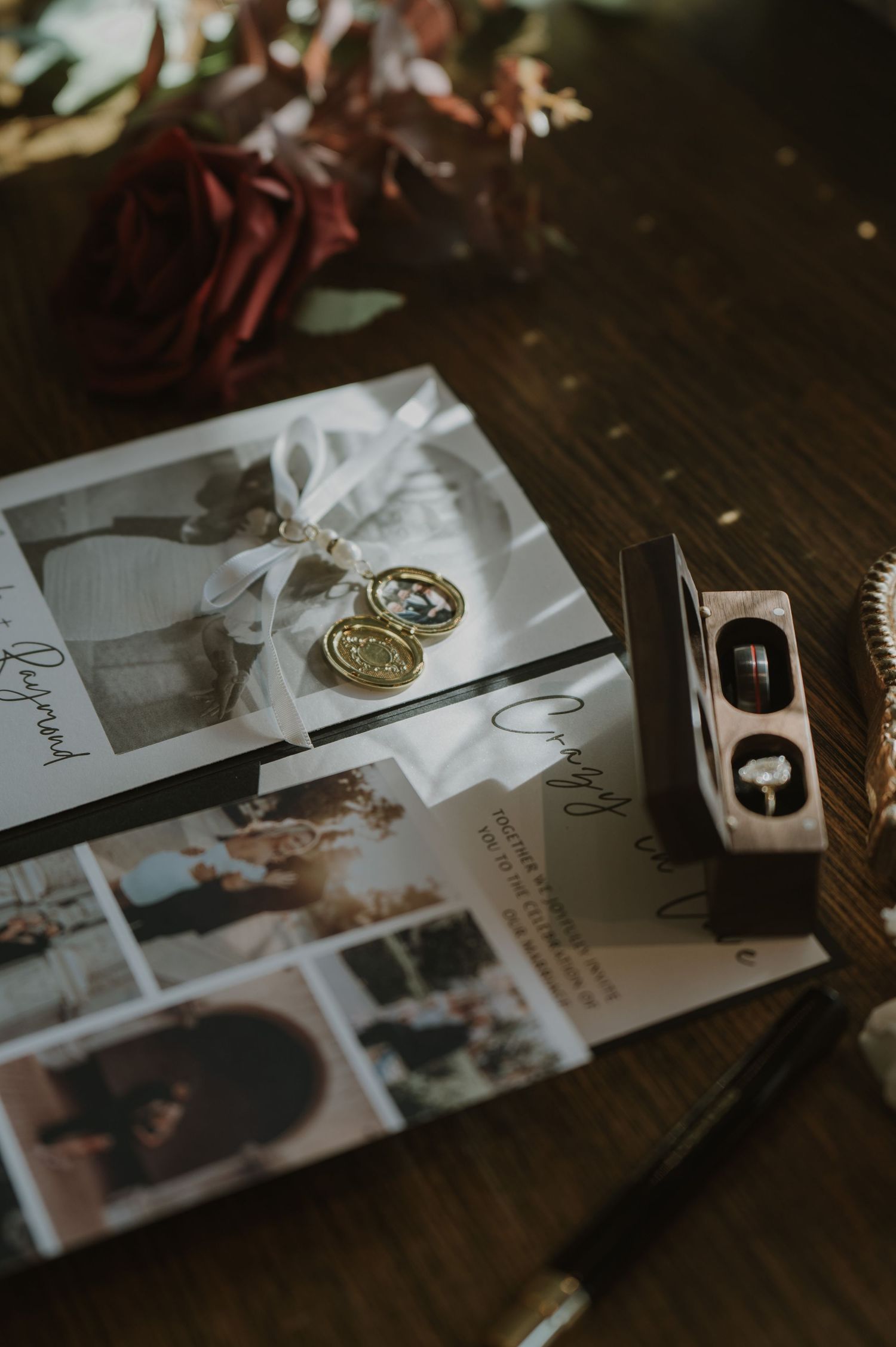 Wedding rings and photographs scattered artistically on a dark wooden surface.