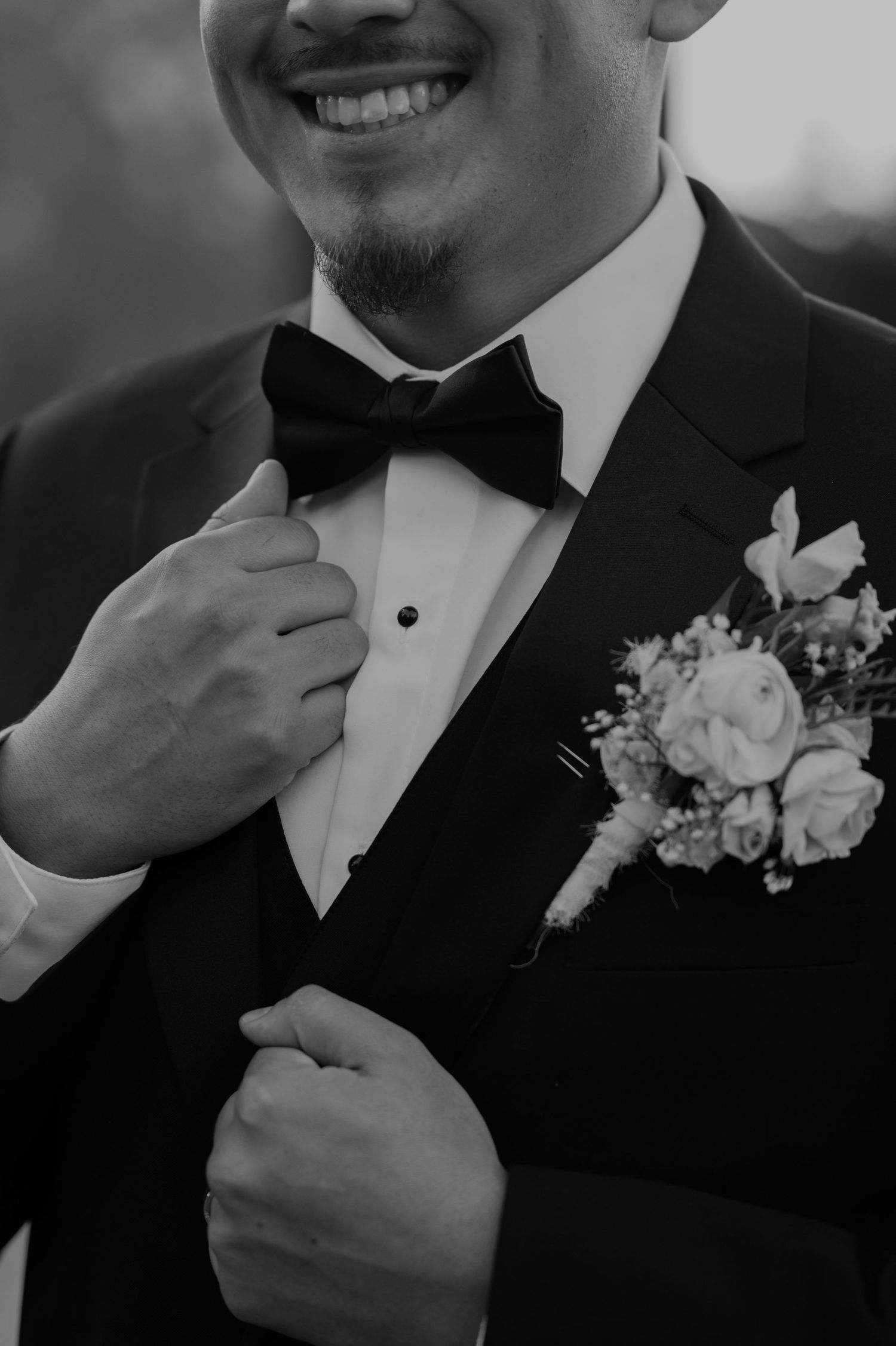 Close-up of groom in tuxedo with black bow tie and floral boutonniere.