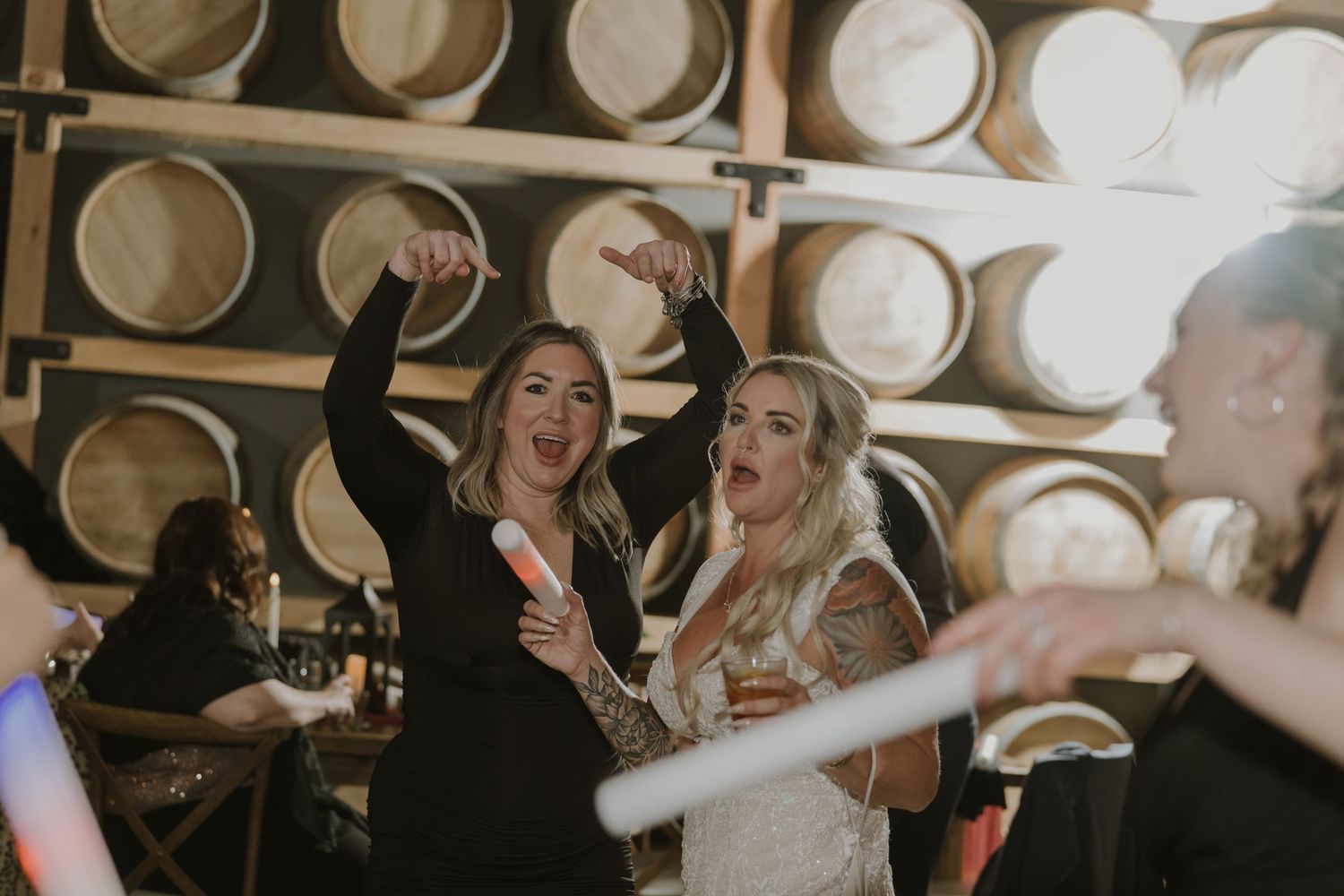 Wedding party dancing and celebrating in rustic barrel room setting.