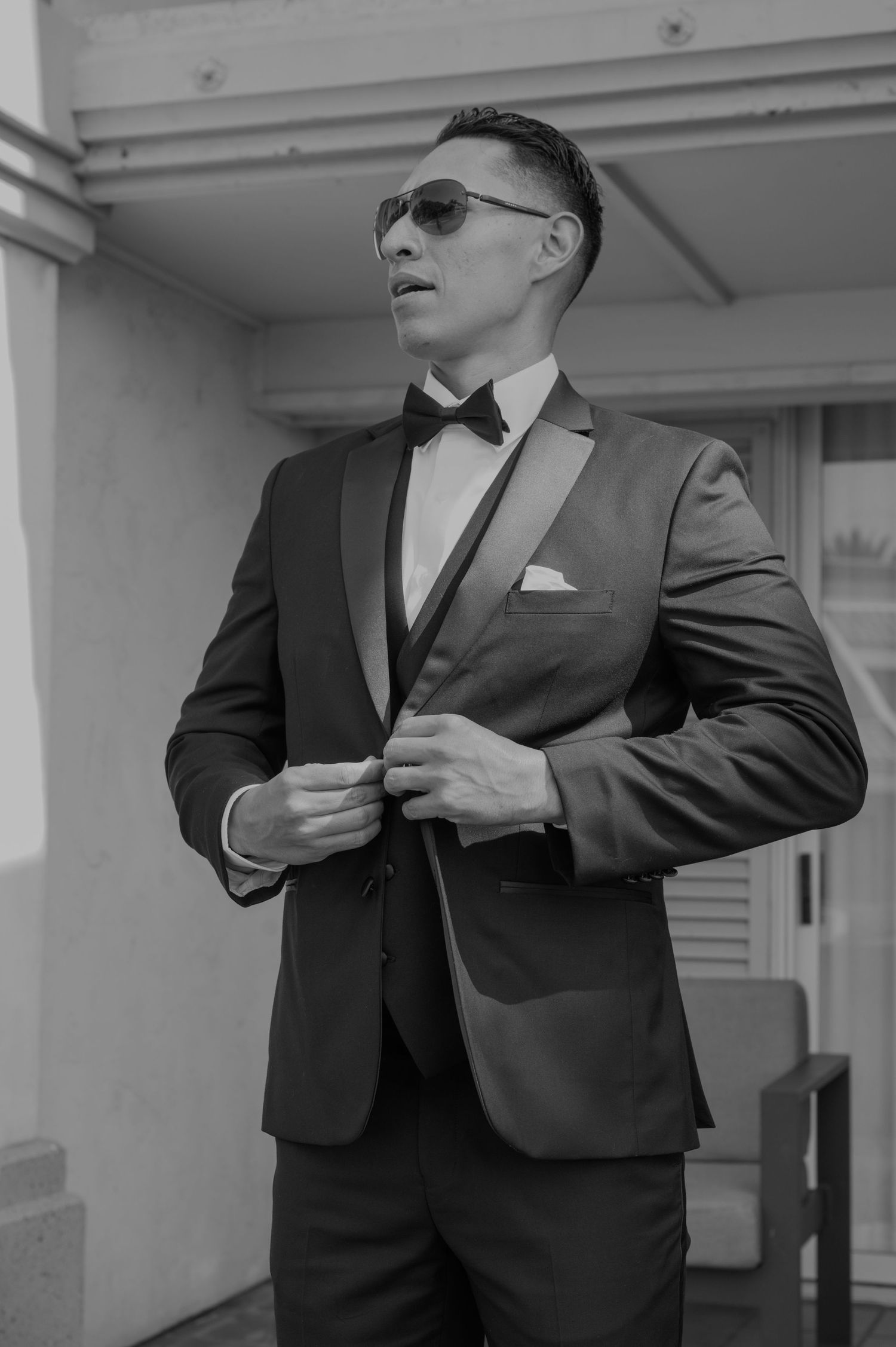 A groom adjusts his tie and suit in a series of black and white preparation photos.