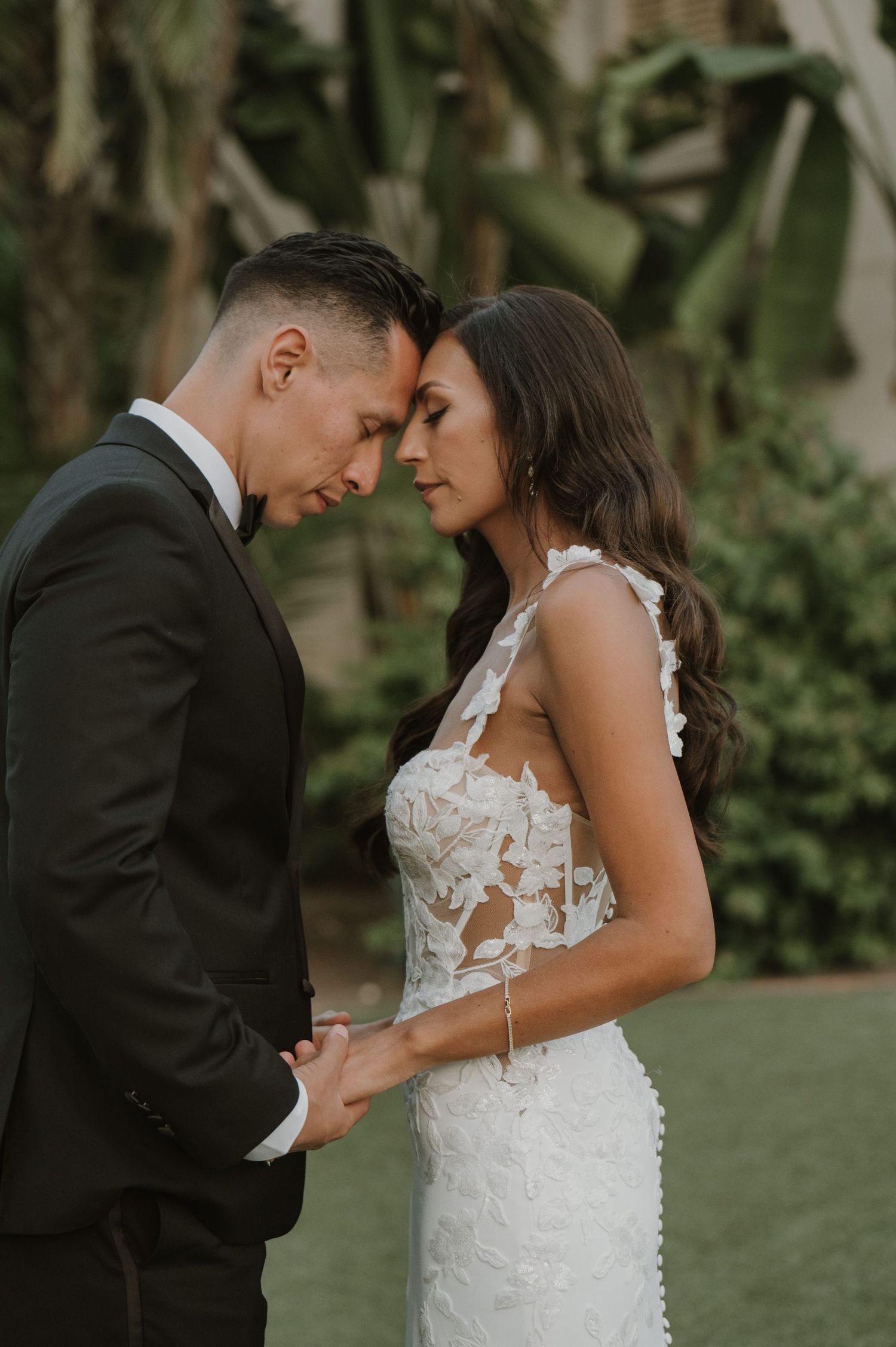An intimate wedding portrait captured in a lush garden setting at dusk.