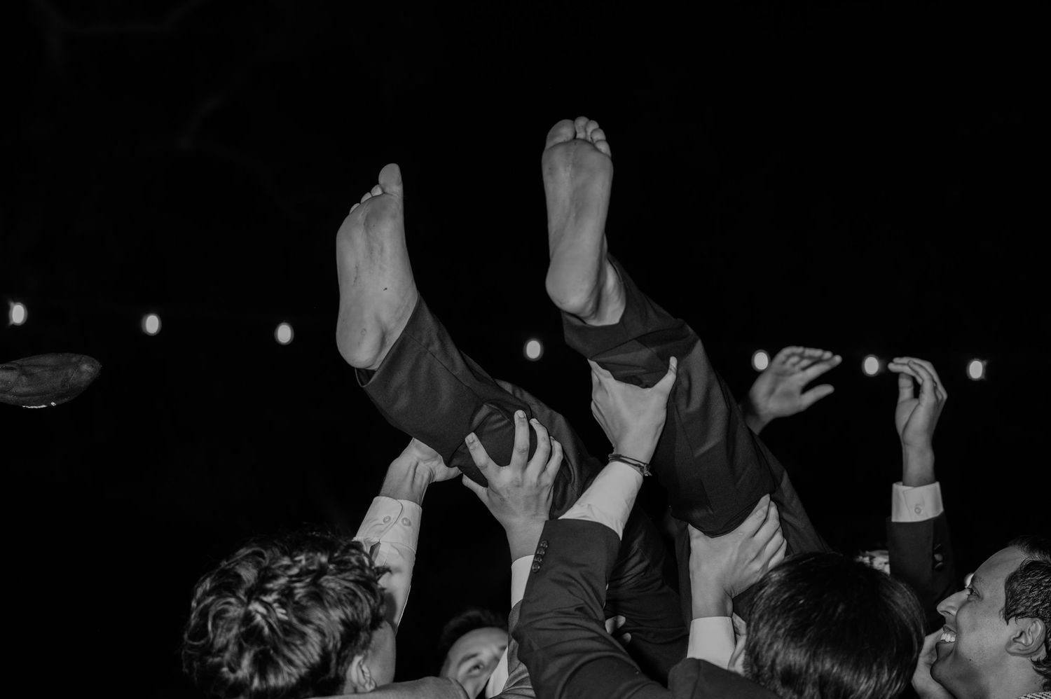 Crowd celebrating with raised hands at a nighttime wedding reception.