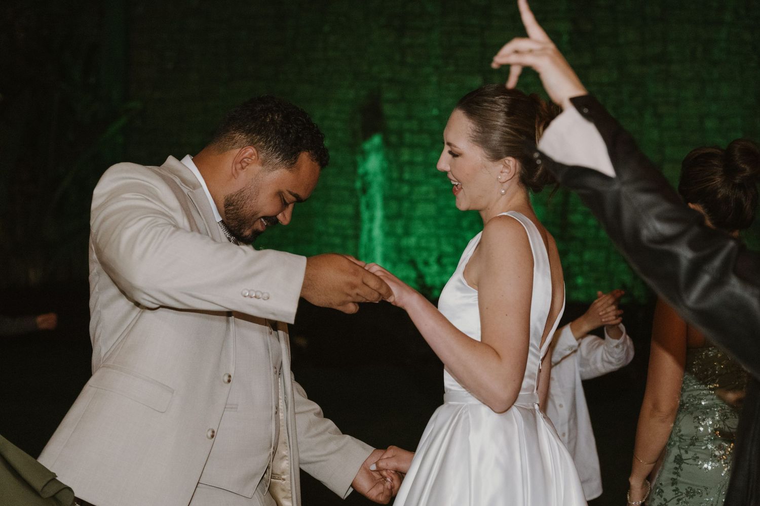 Bride and groom sharing a joyful dance together at their wedding reception with guests celebrating.