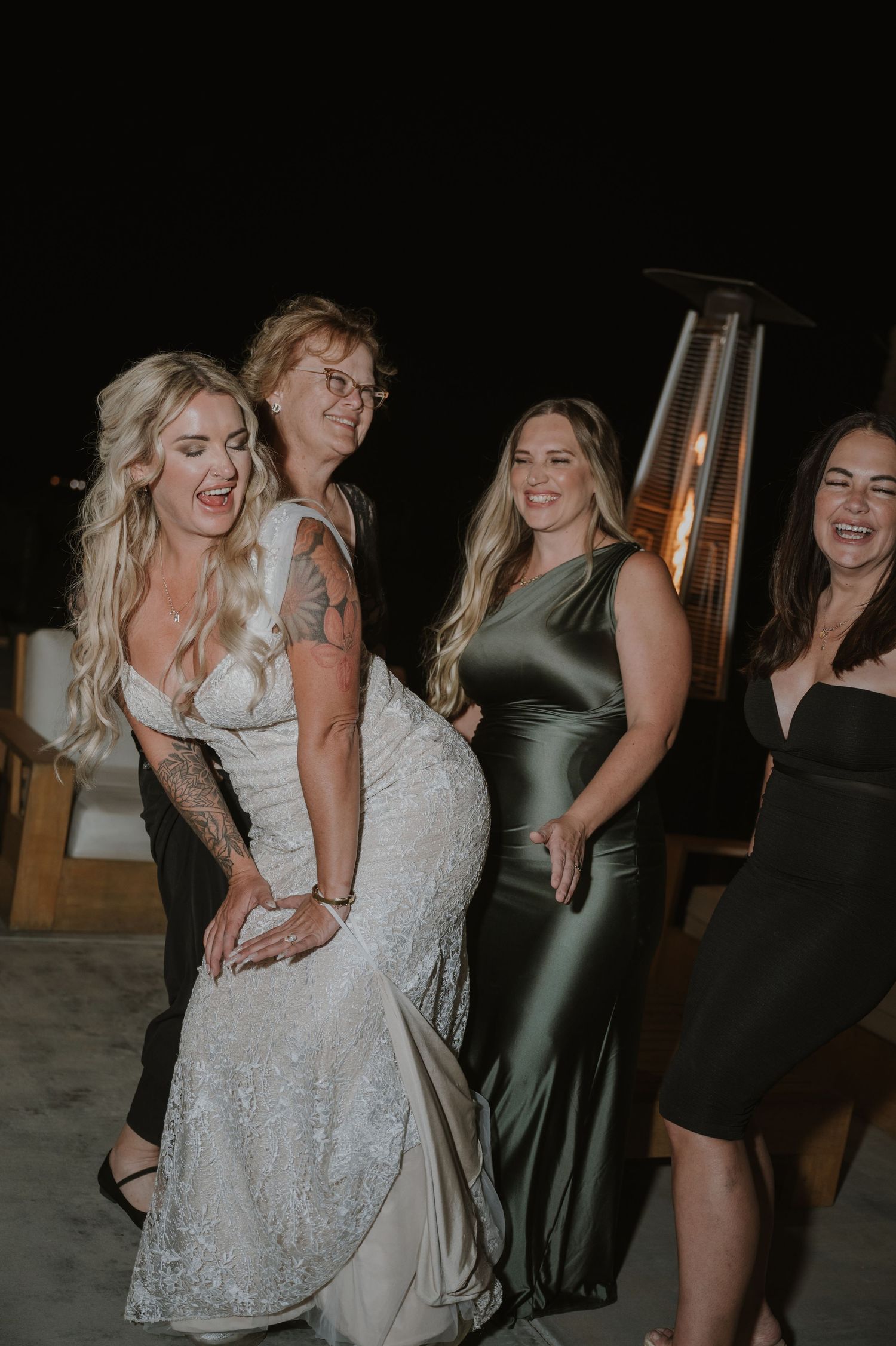 Wedding celebration with guests dancing in formal attire at dimly lit venue.