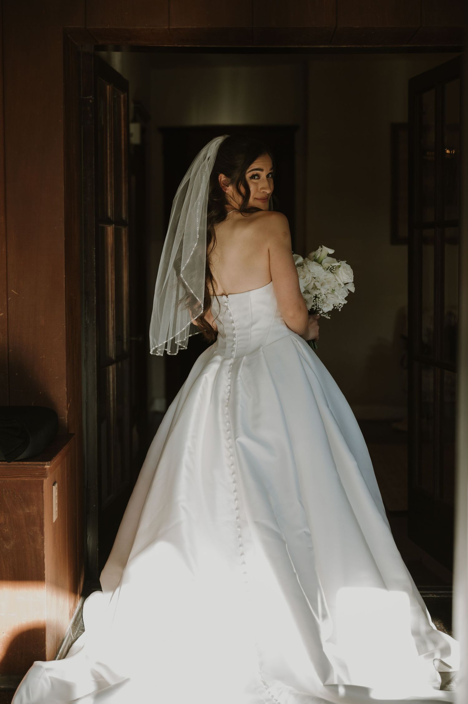 Back view of an elegant white wedding gown with button details and flowing train.