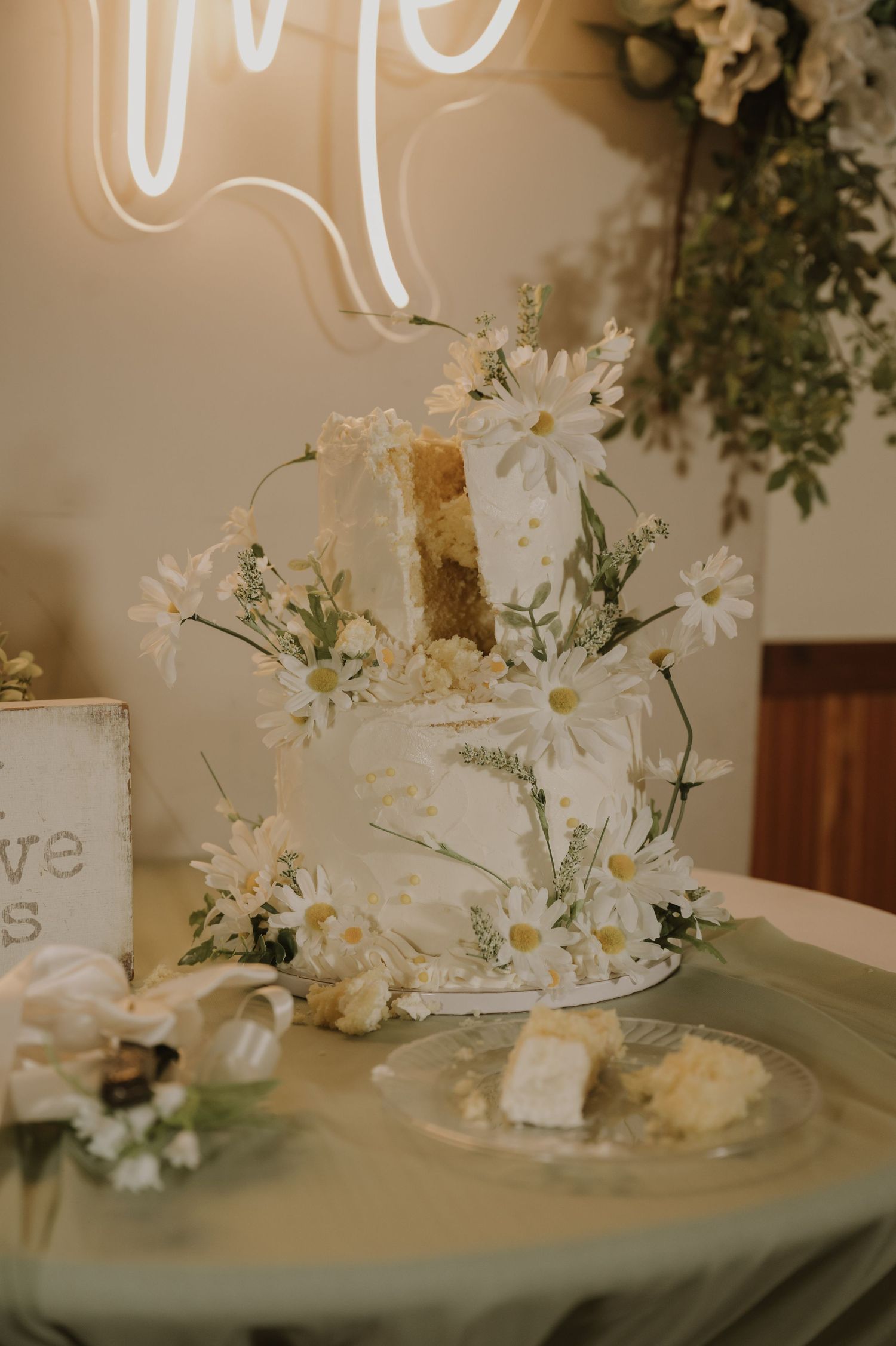 White daisies in vases with decorative signage create an elegant table centerpiece display.