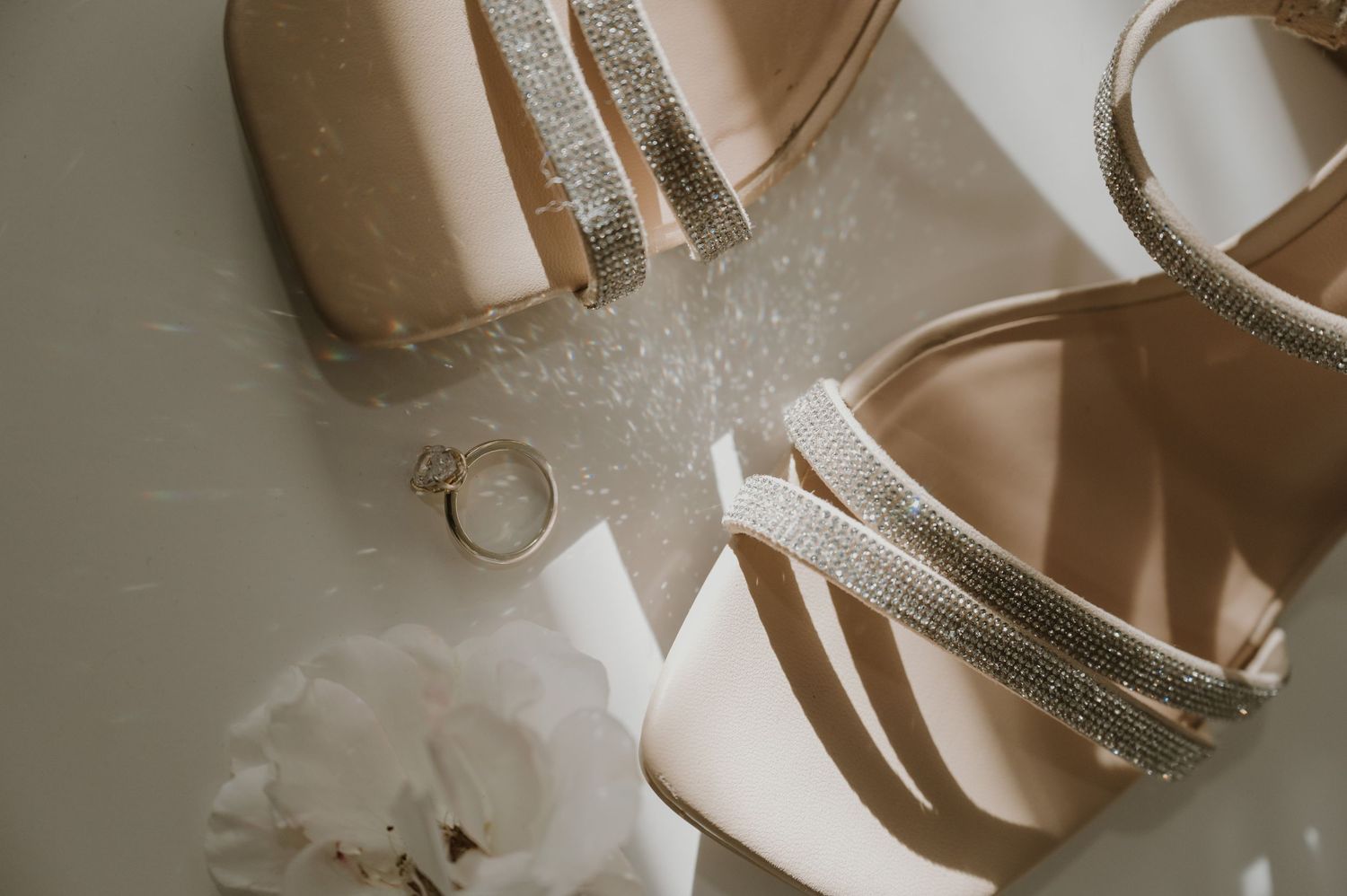 Sparkly bridal shoes and wedding accessories arranged on a light surface.
