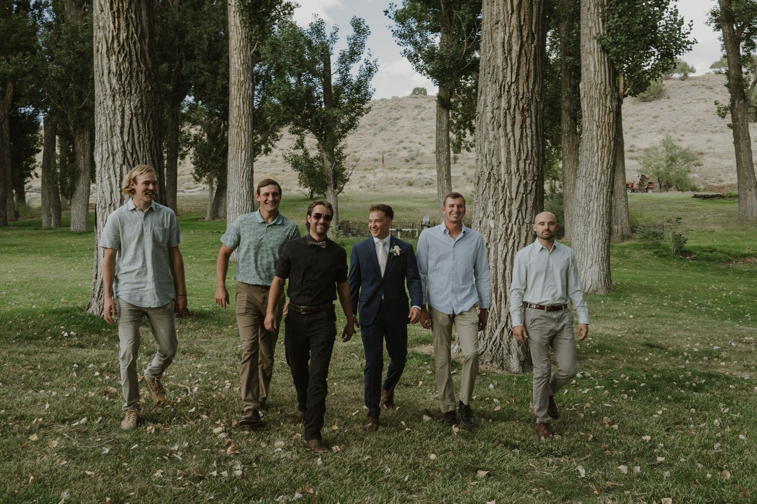 Group of people standing among tall trees in an outdoor setting.