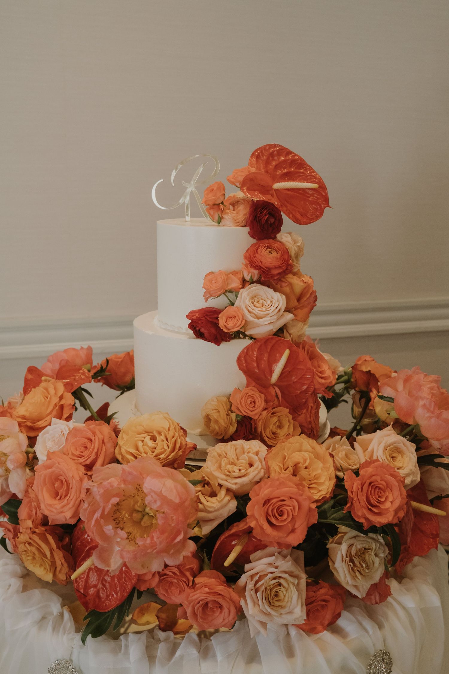 Stunning coral and peach rose floral arrangement adorning a white wedding cake.
