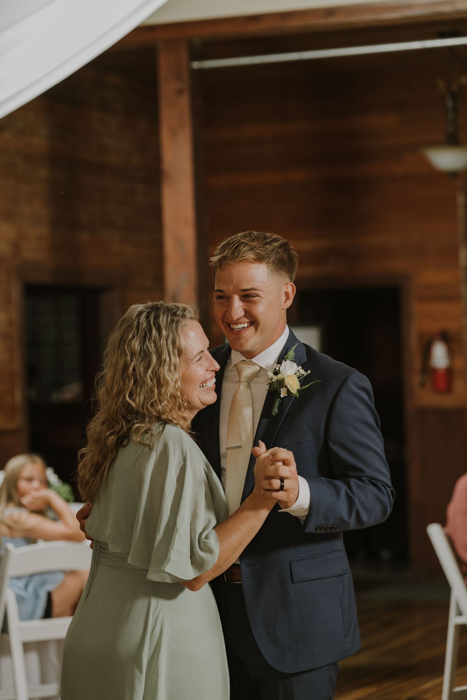 A couple shares a tender moment during their first dance at a rustic barn wedding reception.