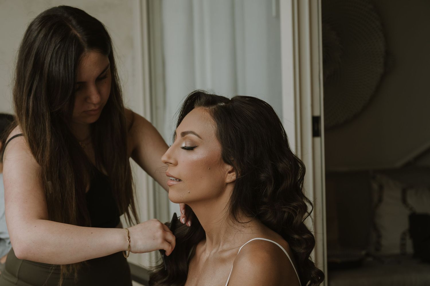 Bride getting ready in a white dress with soft window lighting.