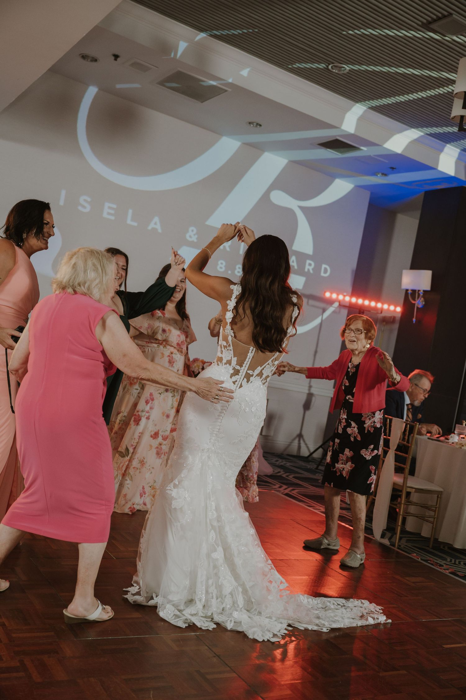 Wedding party dancing on illuminated dance floor with decorative lighting effects.