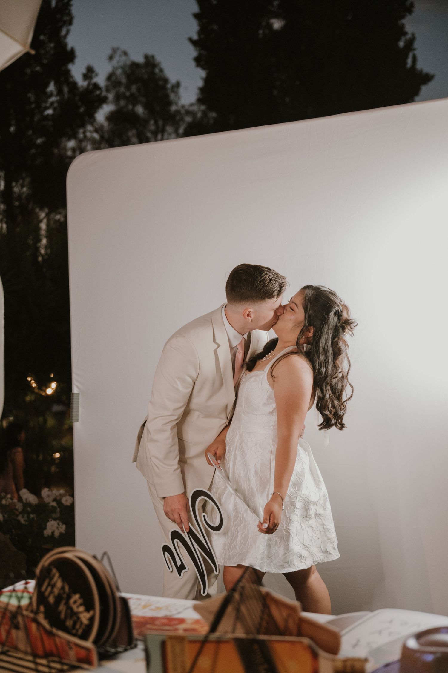 Bride and groom kissing at a wedding photo booth holding a Mr. and Mrs. sign.