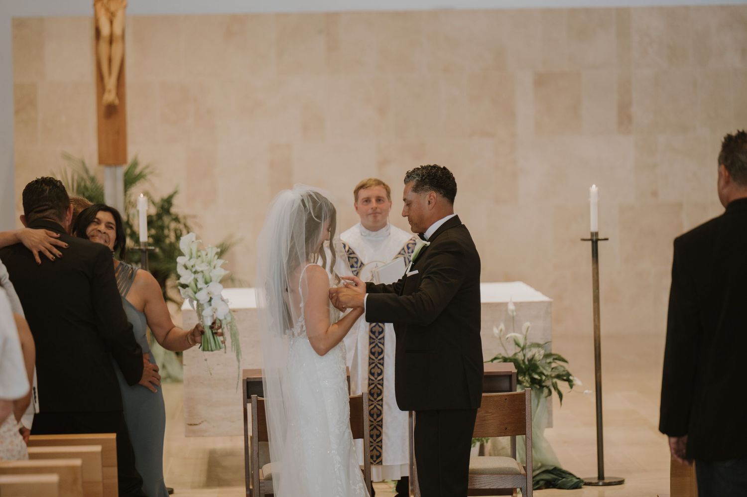 Bride and groom exchange vows at the altar during an elegant Catholic church wedding ceremony.