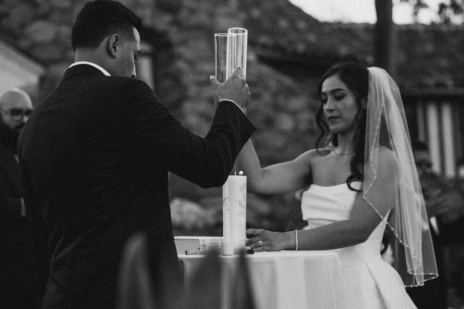 A couple performs a unity ceremony with glass vessels during their wedding.