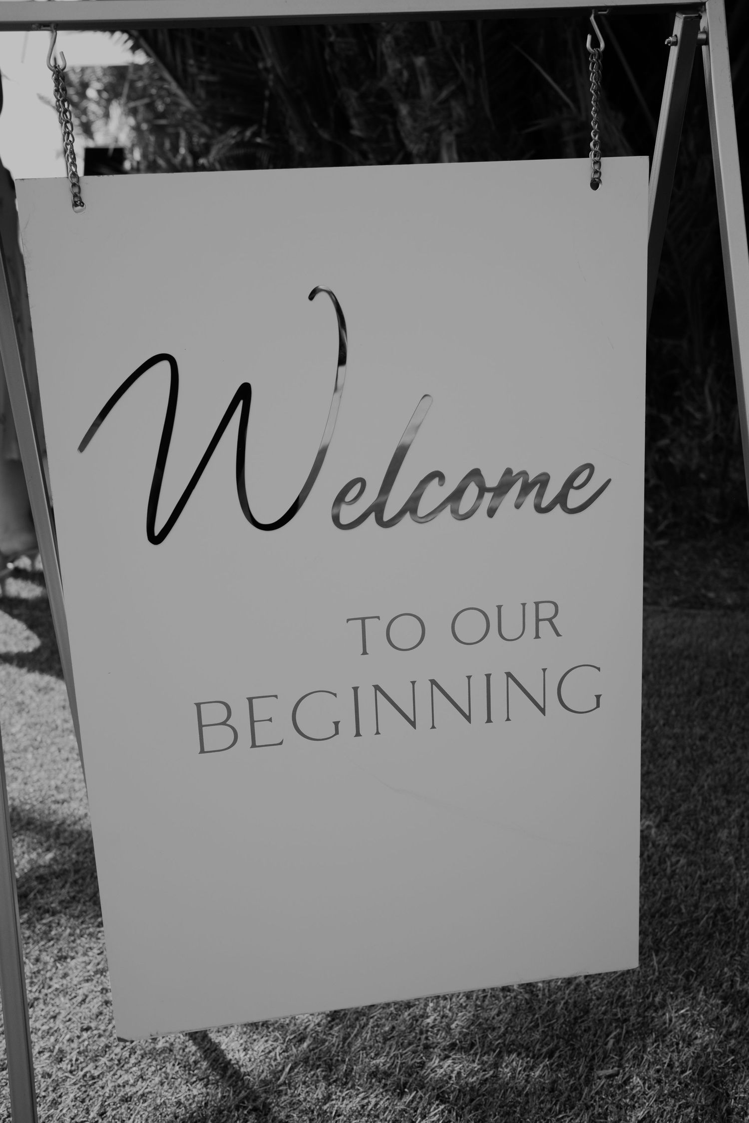 Black and white welcome sign reading 'Welcome to our Beginning' hanging outdoors.