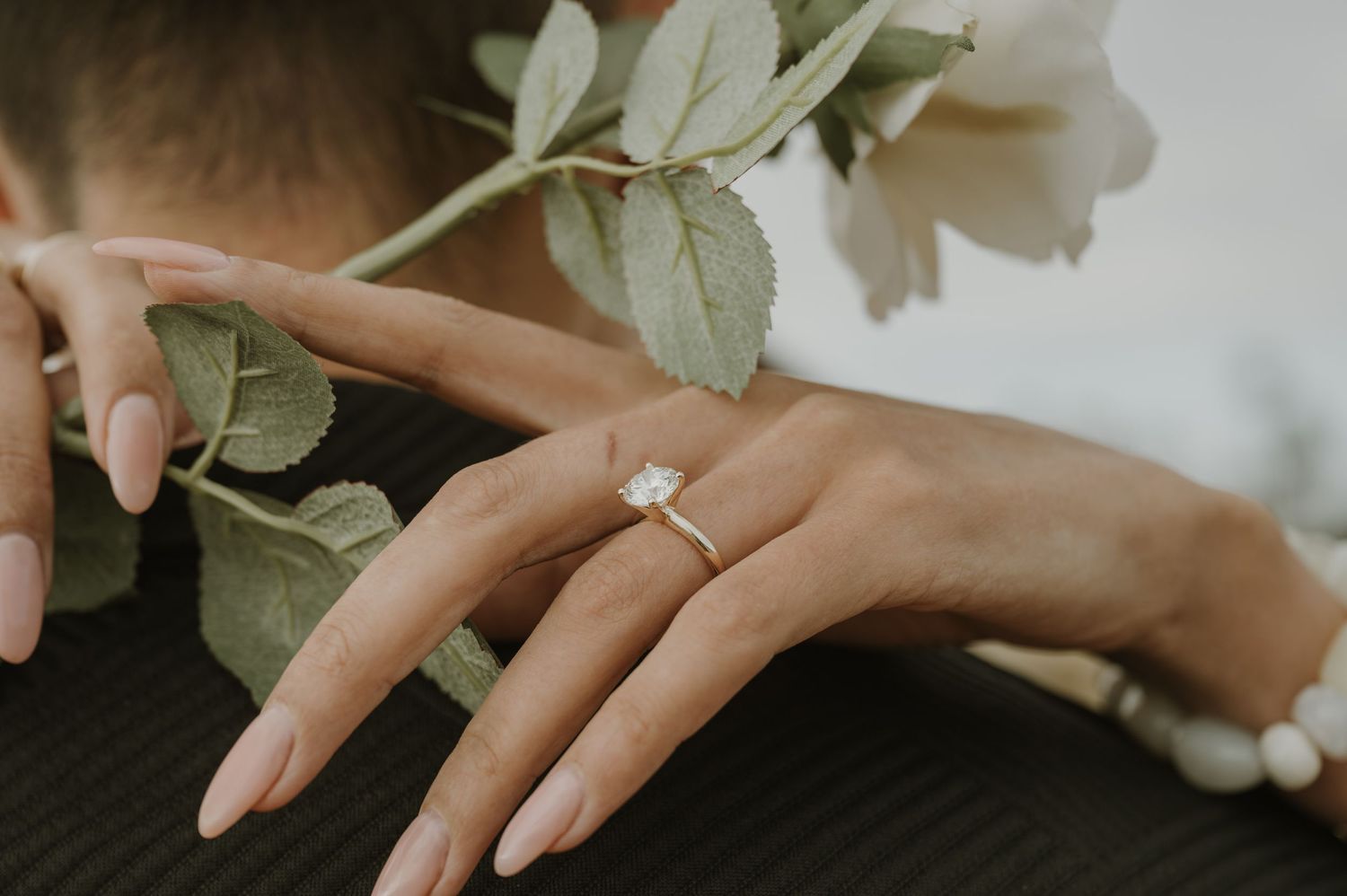 Close-up of hands with wedding rings and delicate white flowers.
