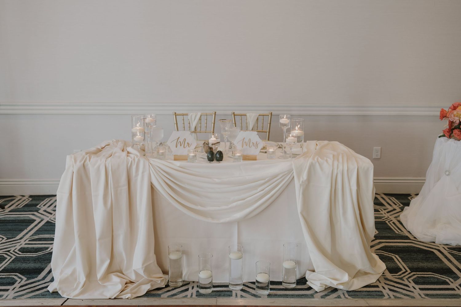 Long white draped tables set up for an elegant wedding reception.