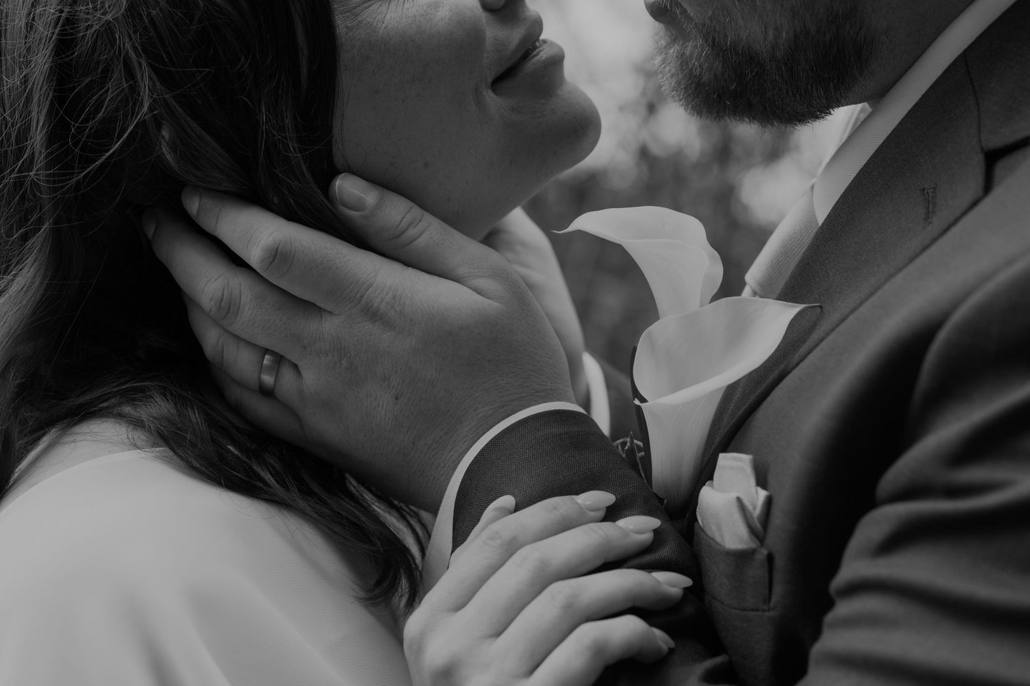 Black and white wedding photo of bride and groom sharing an intimate moment, groom tenderly holding bride's face.